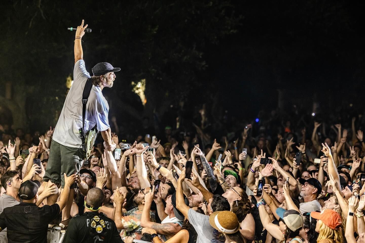 A man is standing on top of a crowd of people at a concert.