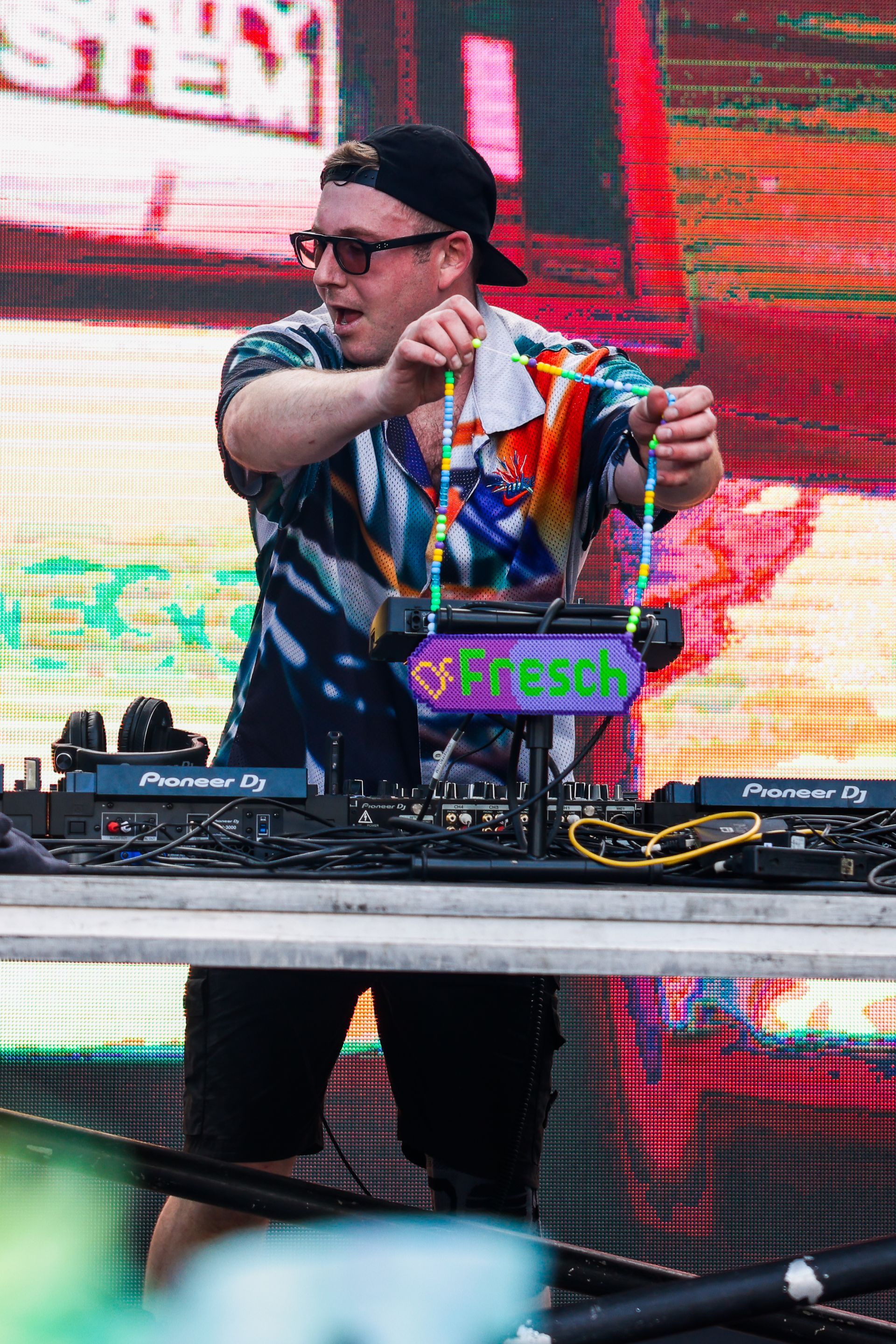A man is playing a dj set on a stage in front of a large screen.