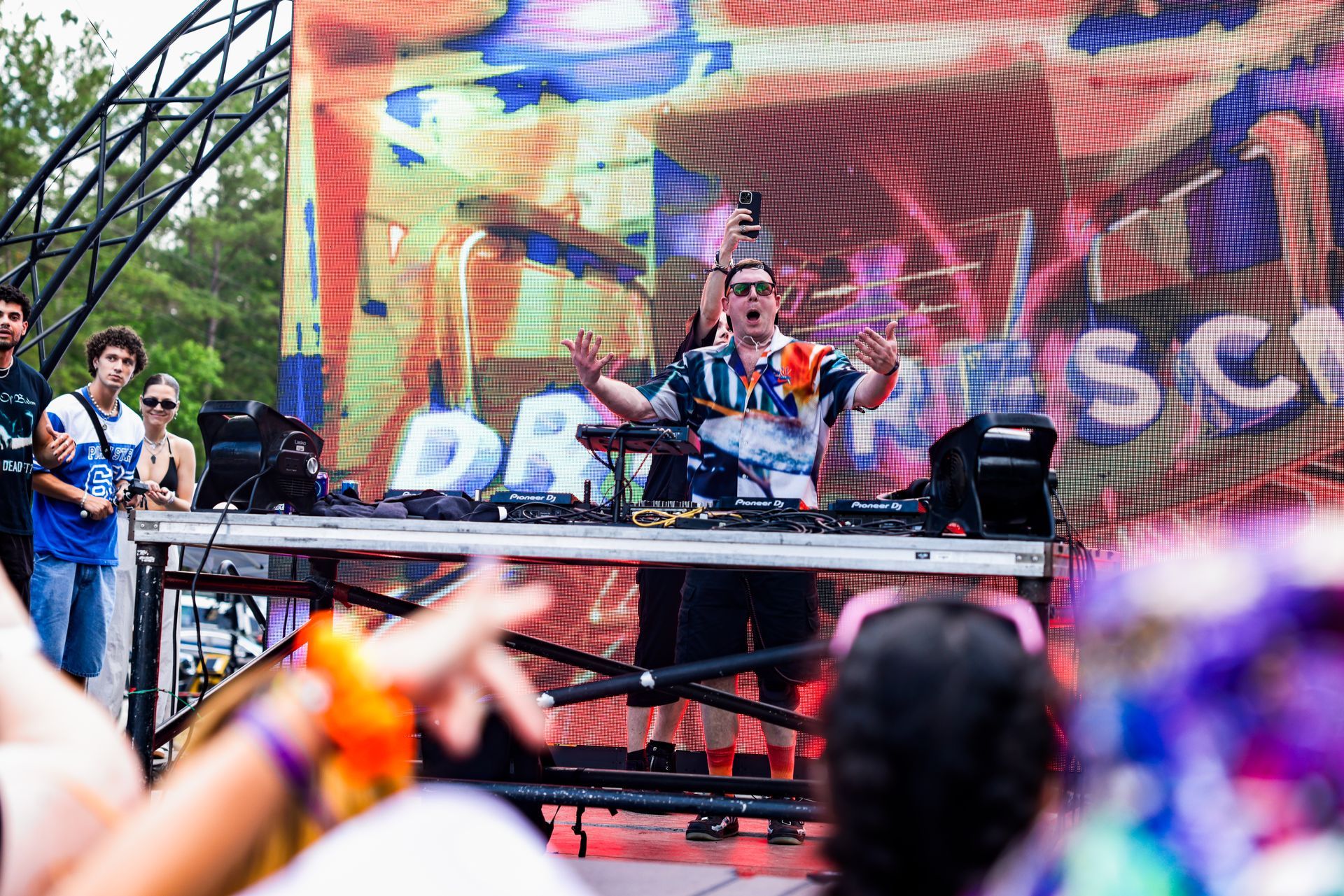 A dj is playing music in front of a crowd at a festival.