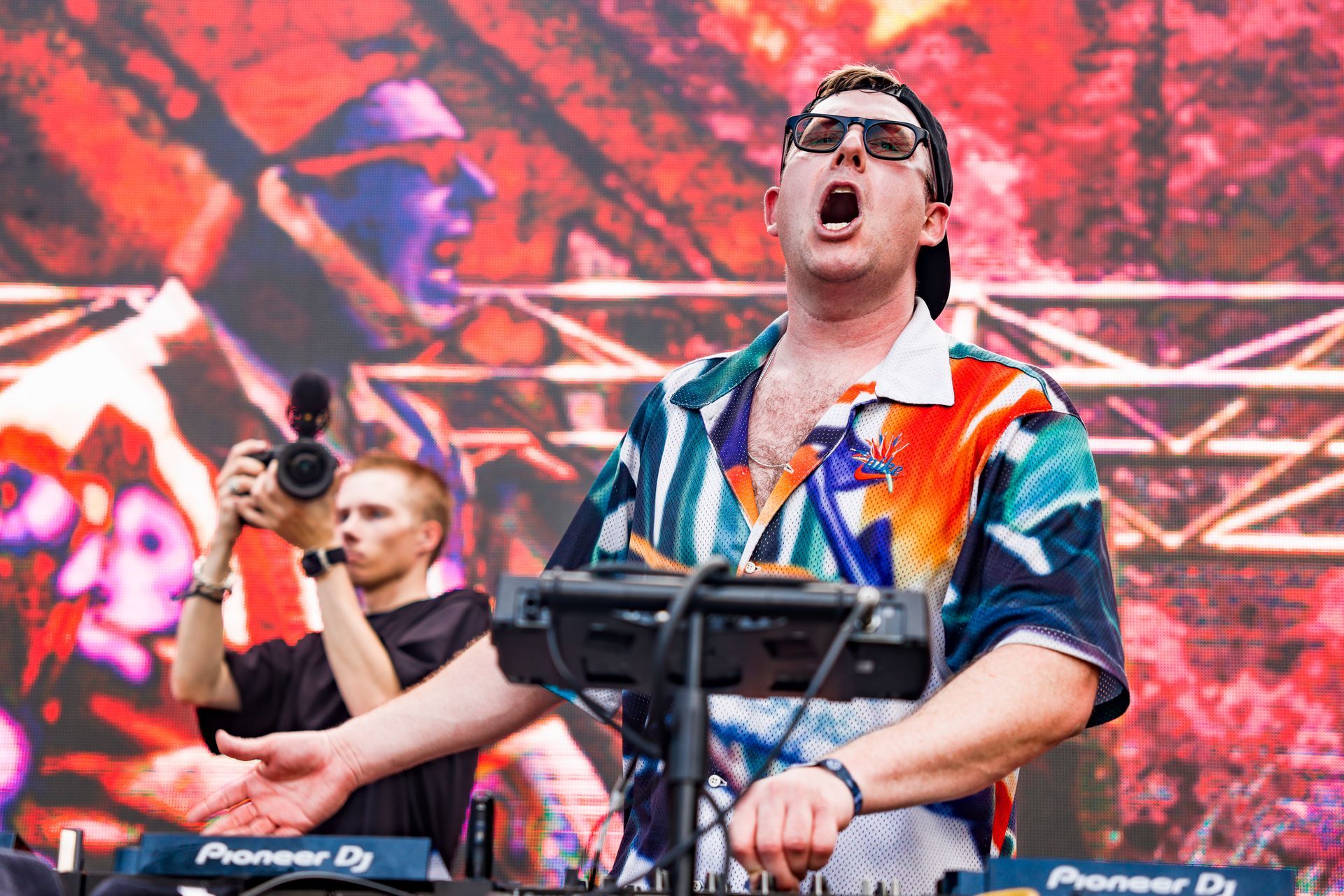 A man in a colorful shirt is playing a keyboard on a stage.