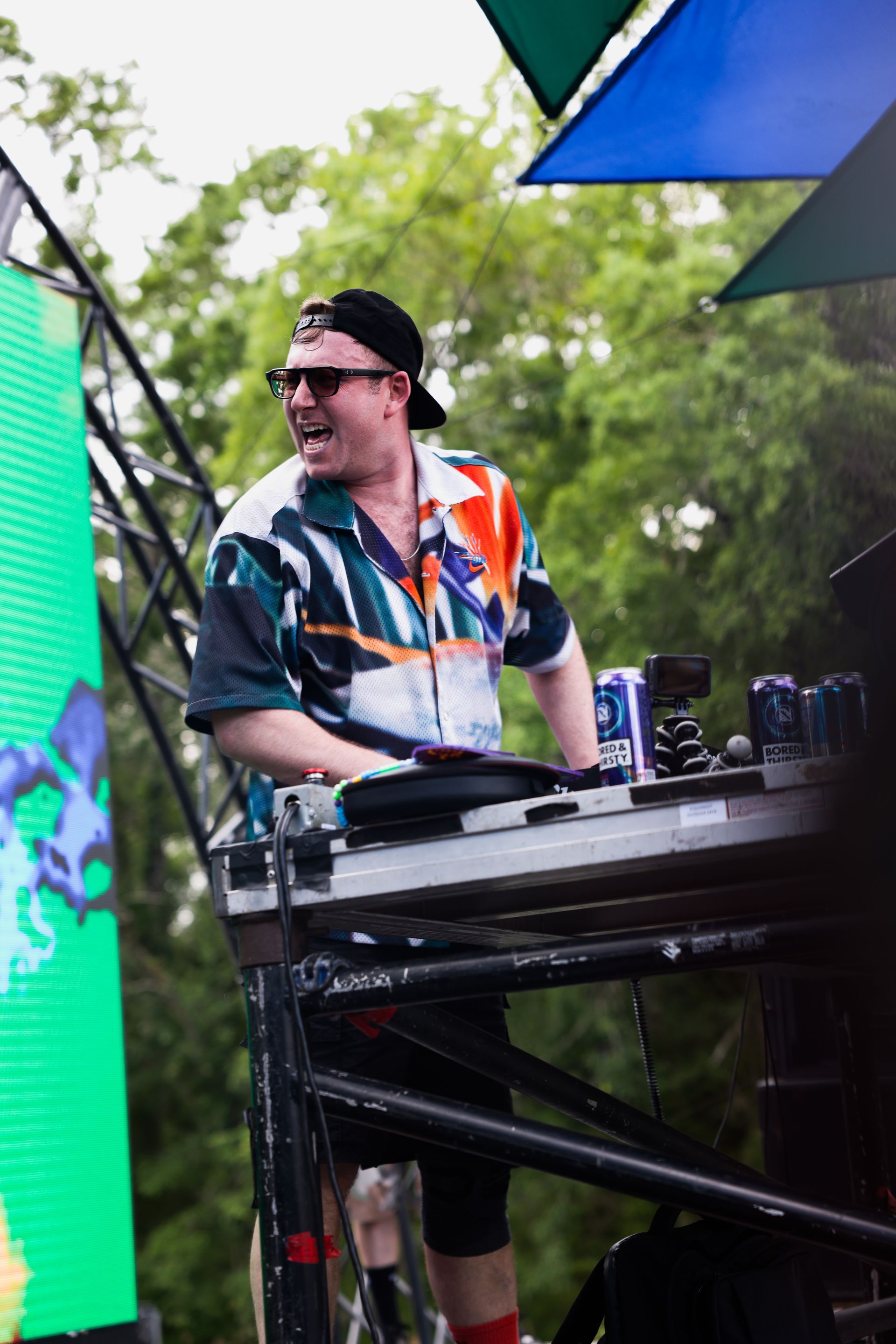 A man in a colorful shirt is playing a dj set on a stage.