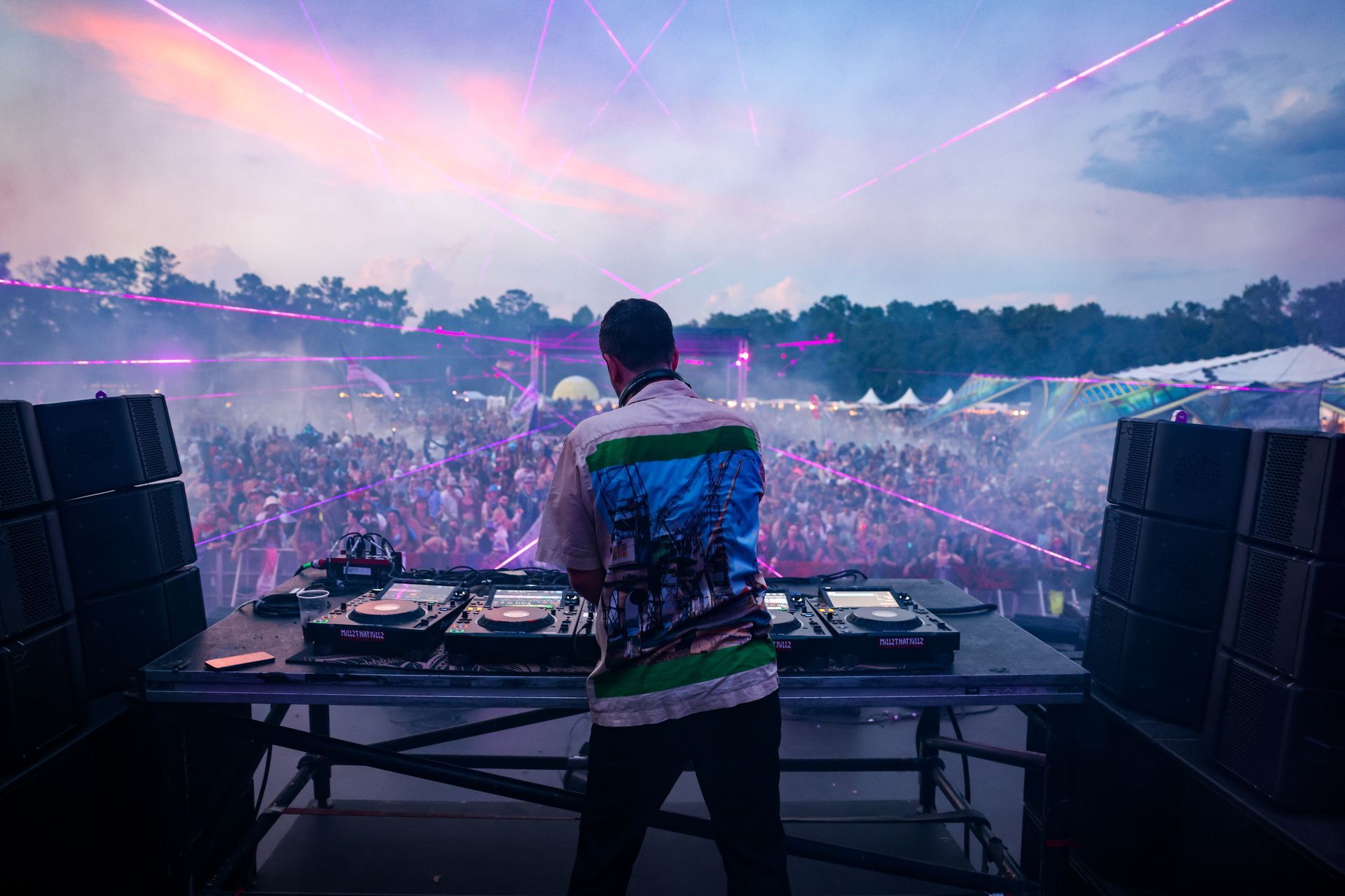 A dj is playing music at a concert in front of a crowd.