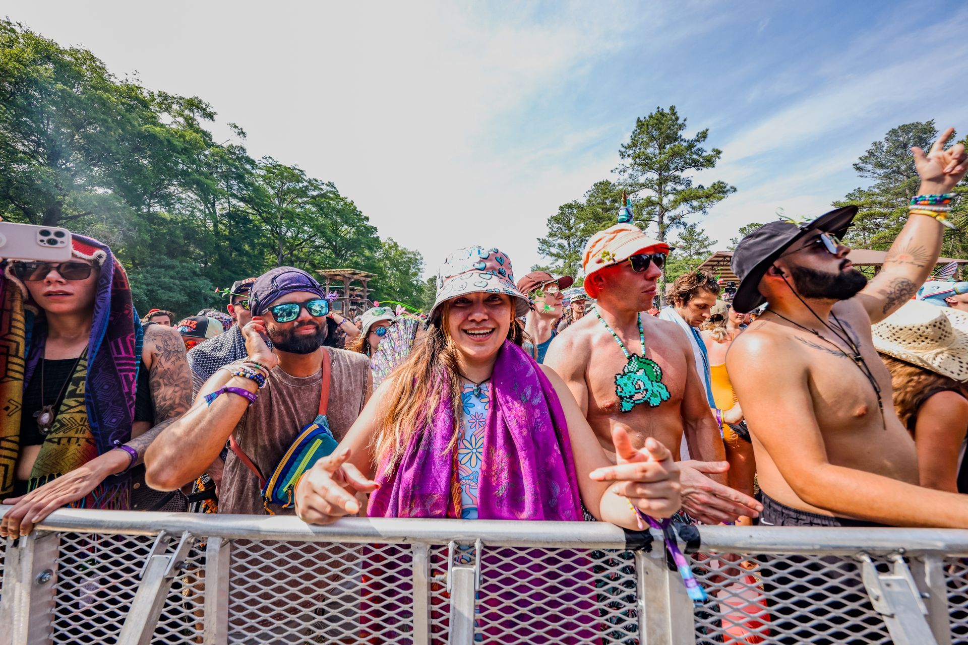 A group of people are standing behind a metal fence at a music festival.