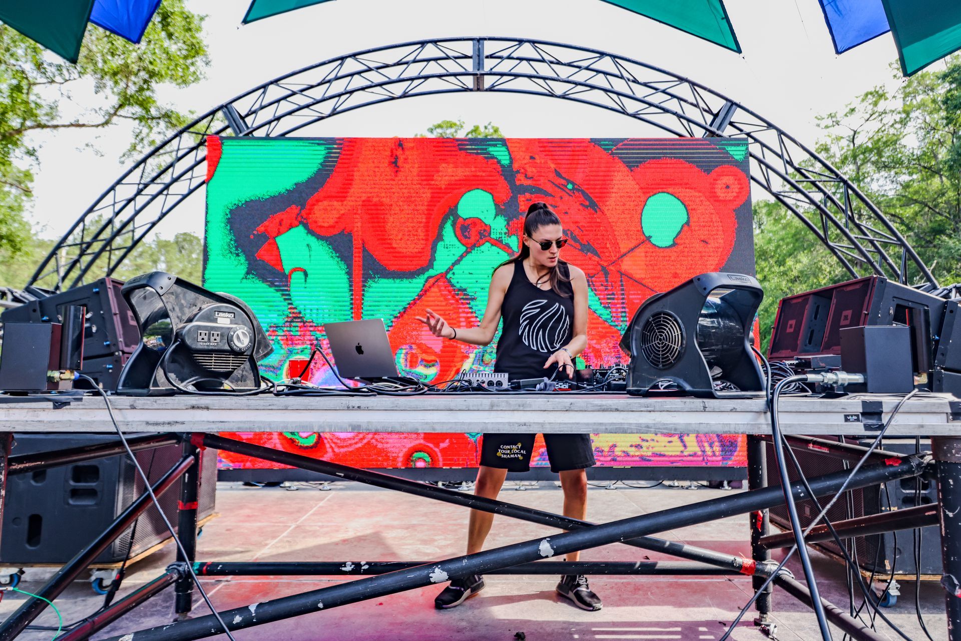 A dj is playing music on a stage in front of a large screen.