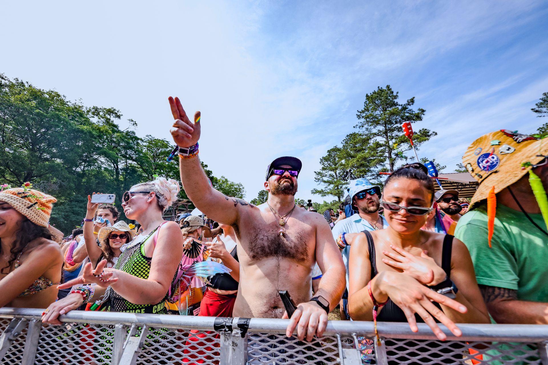 A group of people are standing behind a metal fence at a music festival.