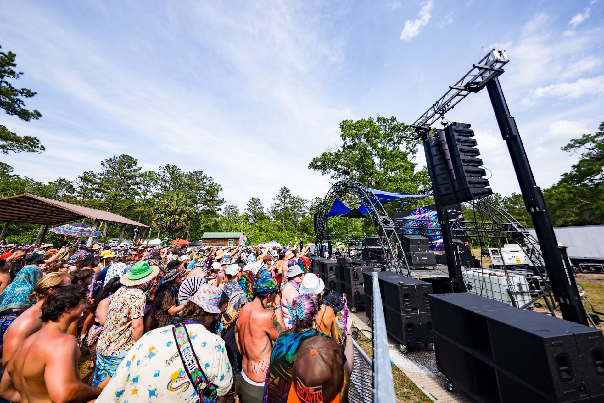 A large group of people are standing in front of a stage at a music festival.