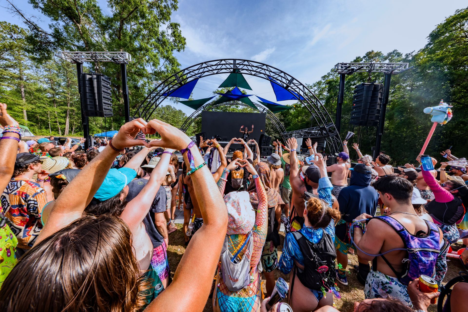 A crowd of people are standing in front of a stage at a music festival.