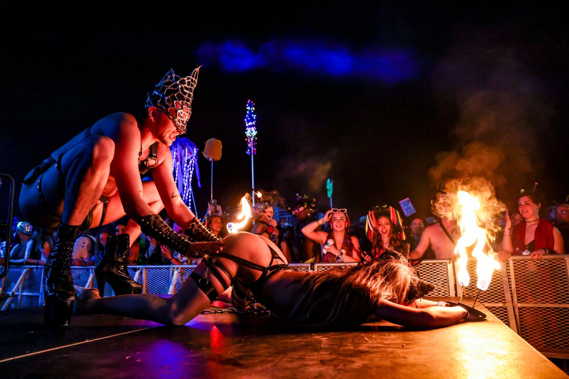 A man and a woman are performing a fire show on a stage in front of a crowd.