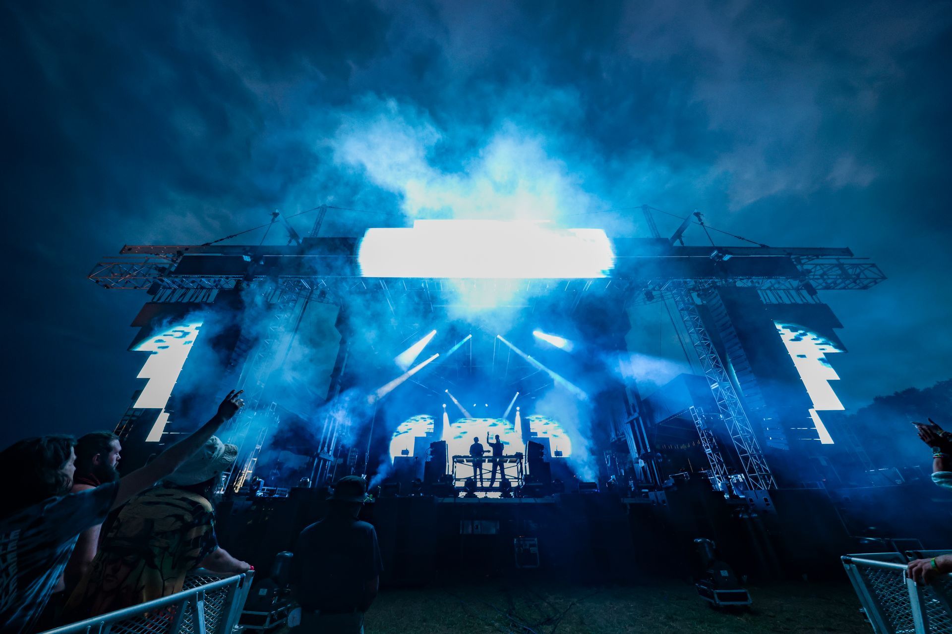 A group of people are standing in front of a stage at a concert.
