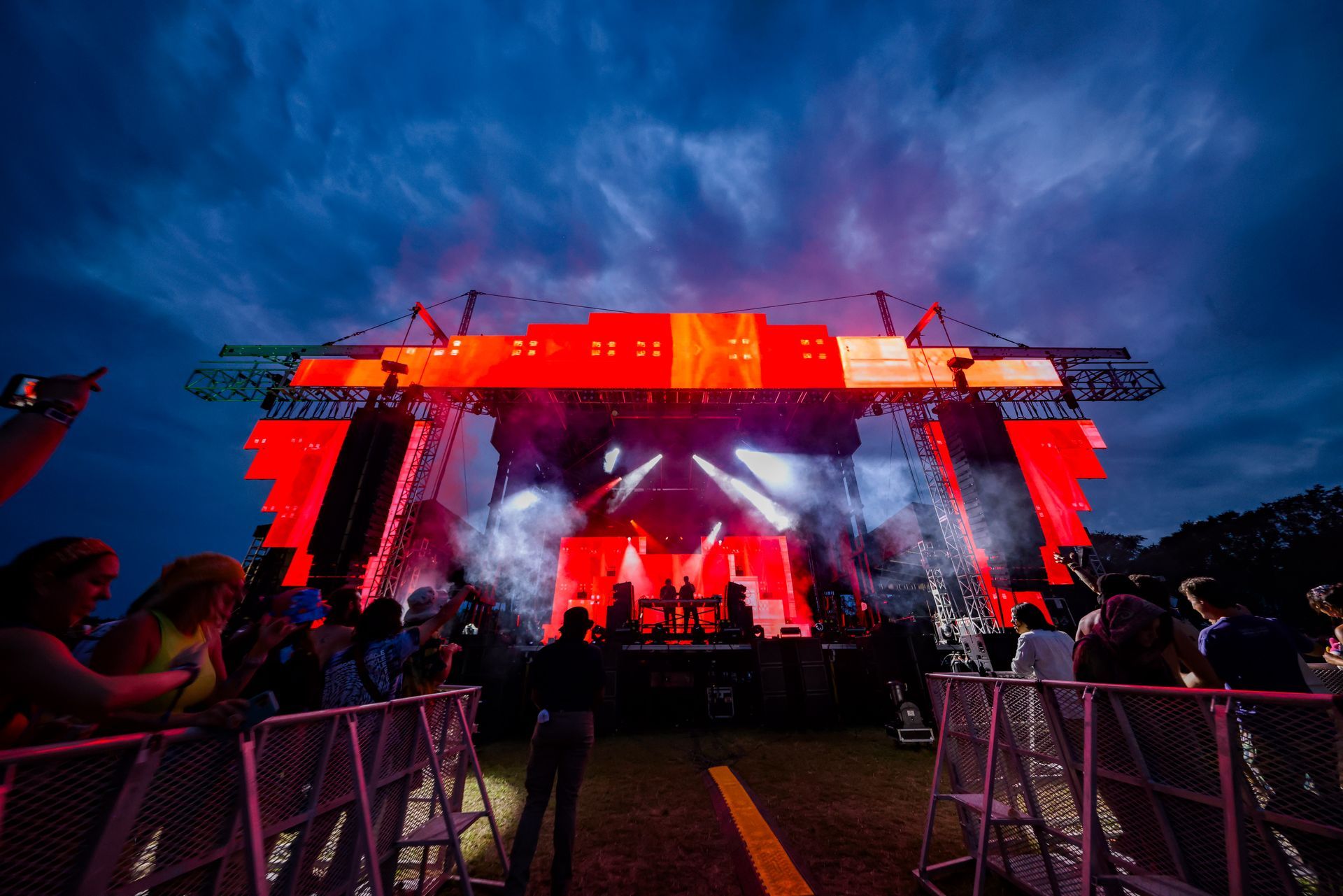A group of people are standing in front of a large stage at a concert.