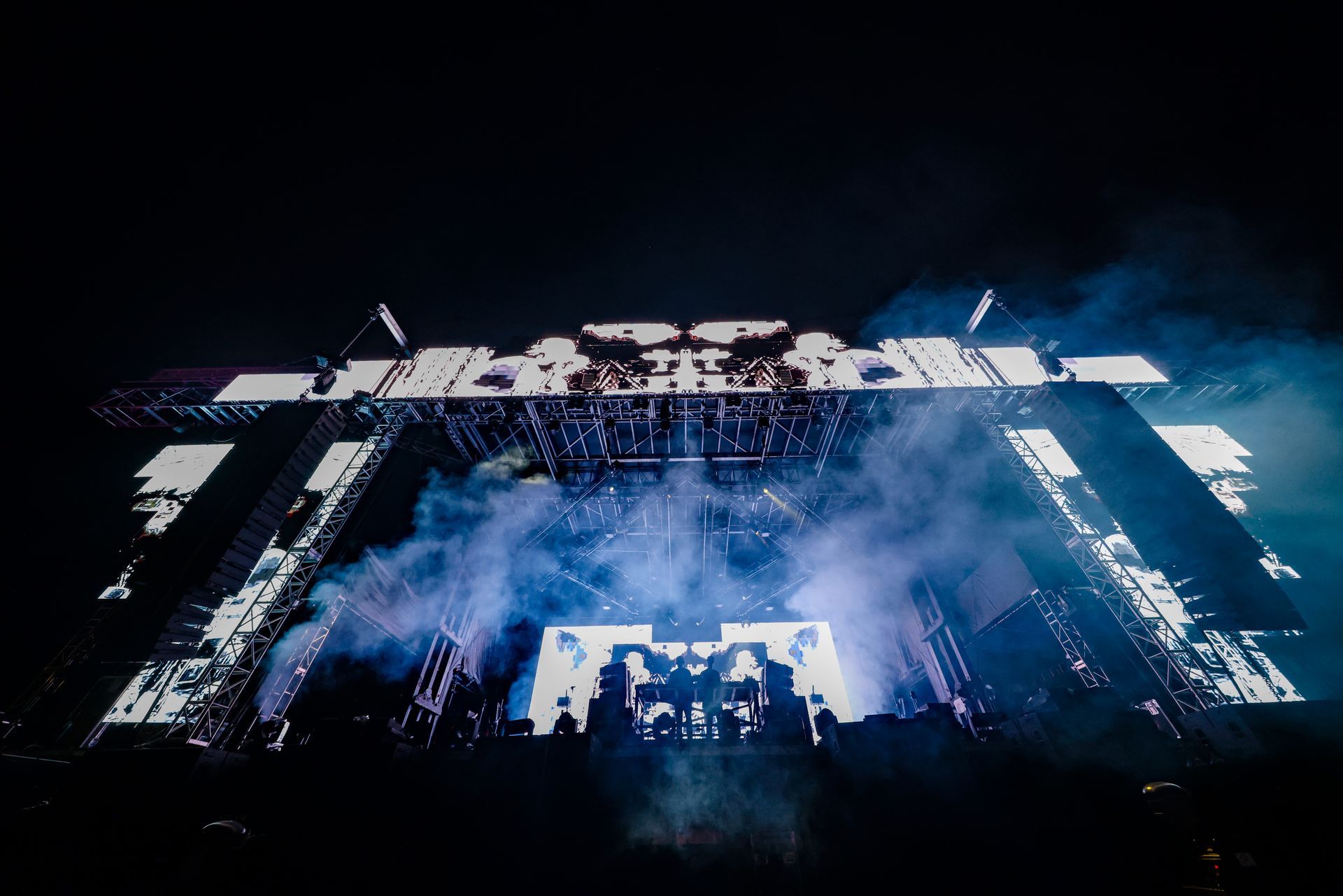 A large stage with smoke coming out of it at a concert.