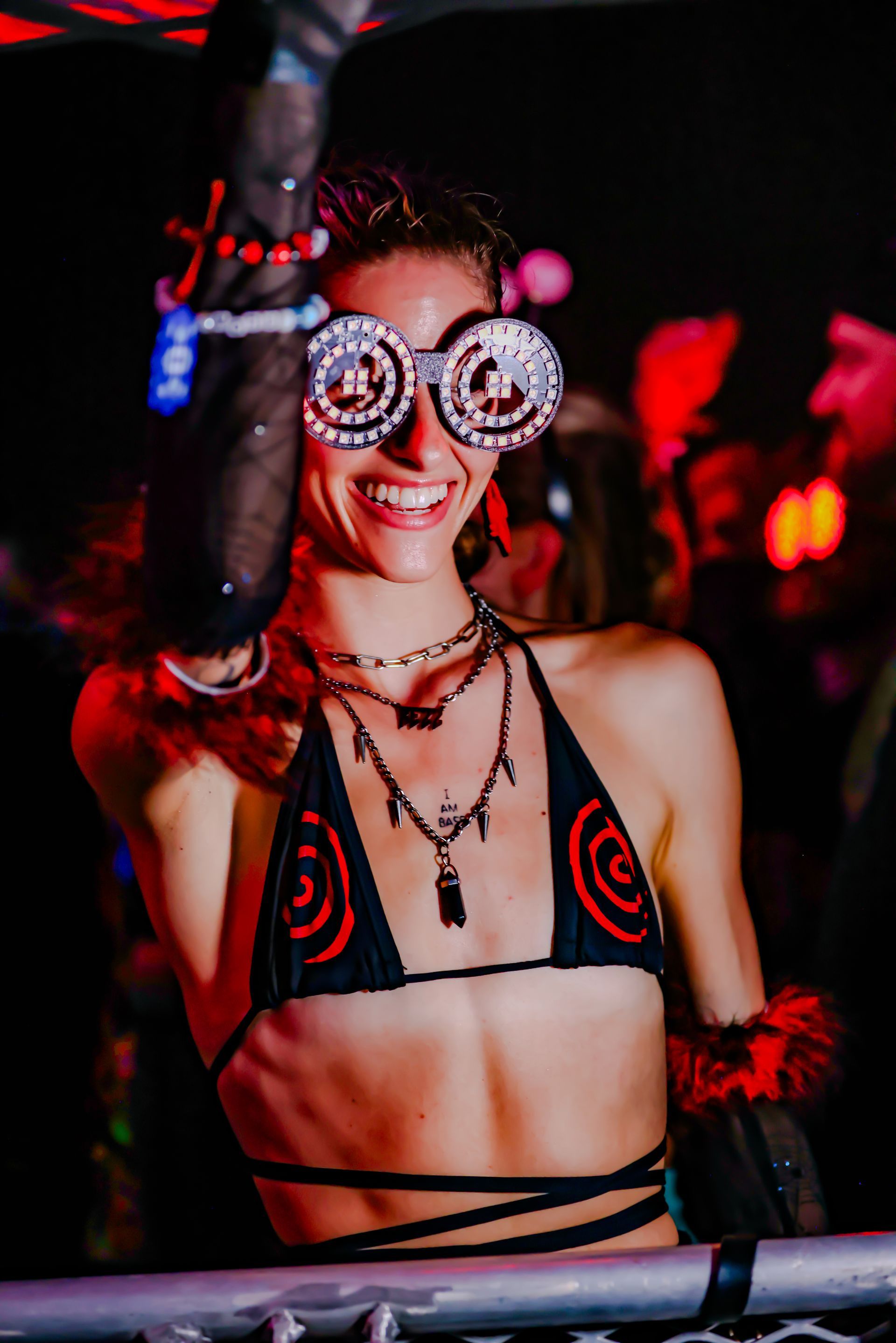 A woman wearing a bikini top and goggles is dancing at a party.