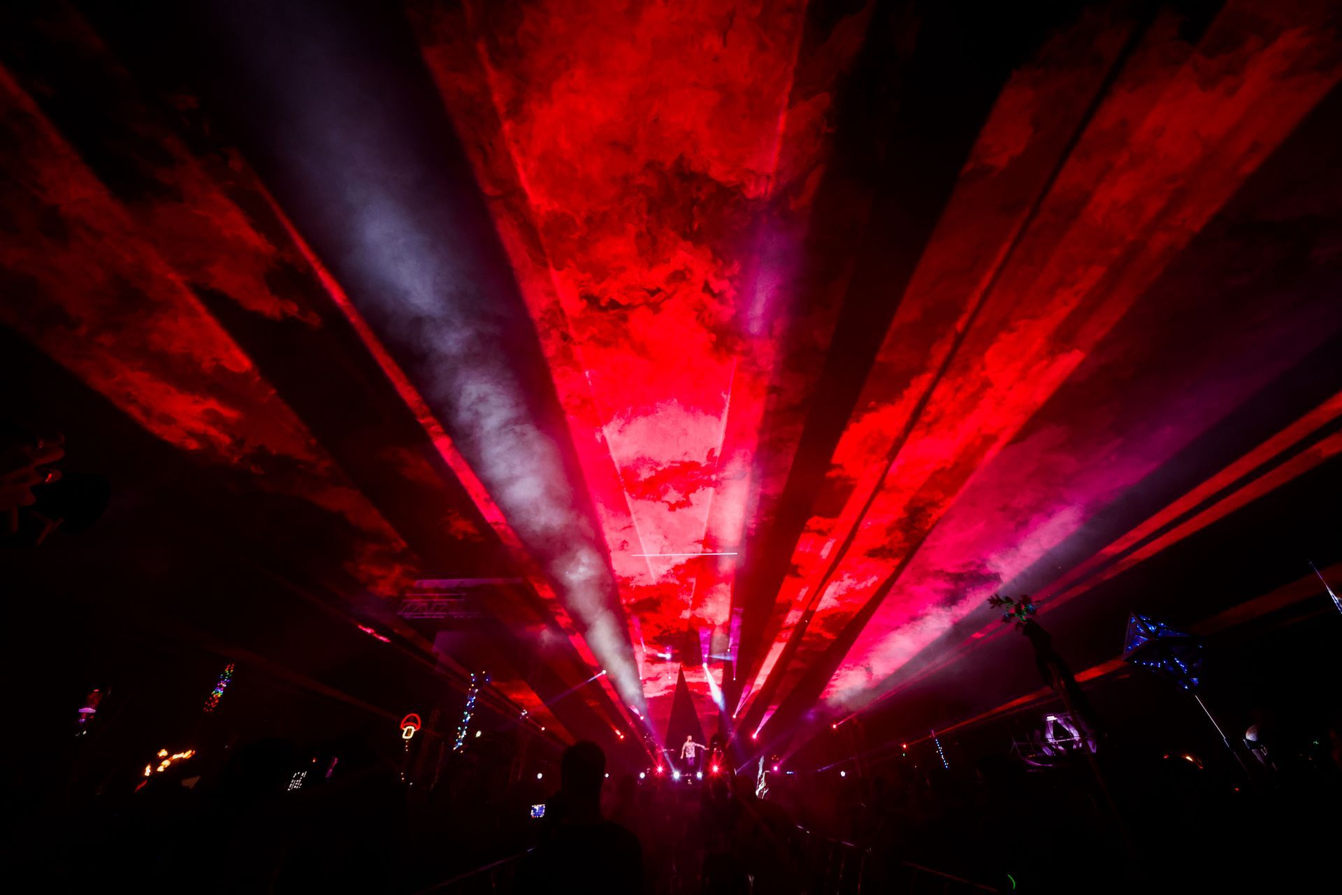 A crowd of people are watching a laser show at a concert.