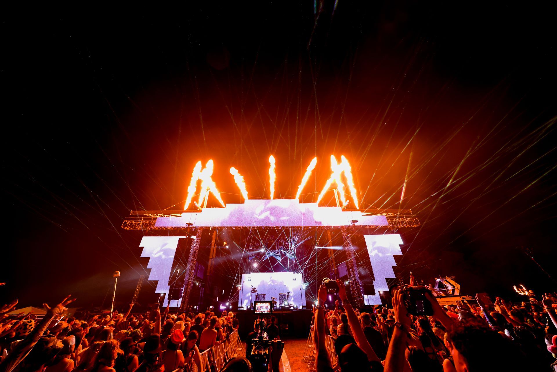 A crowd of people are standing in front of a stage at a concert.