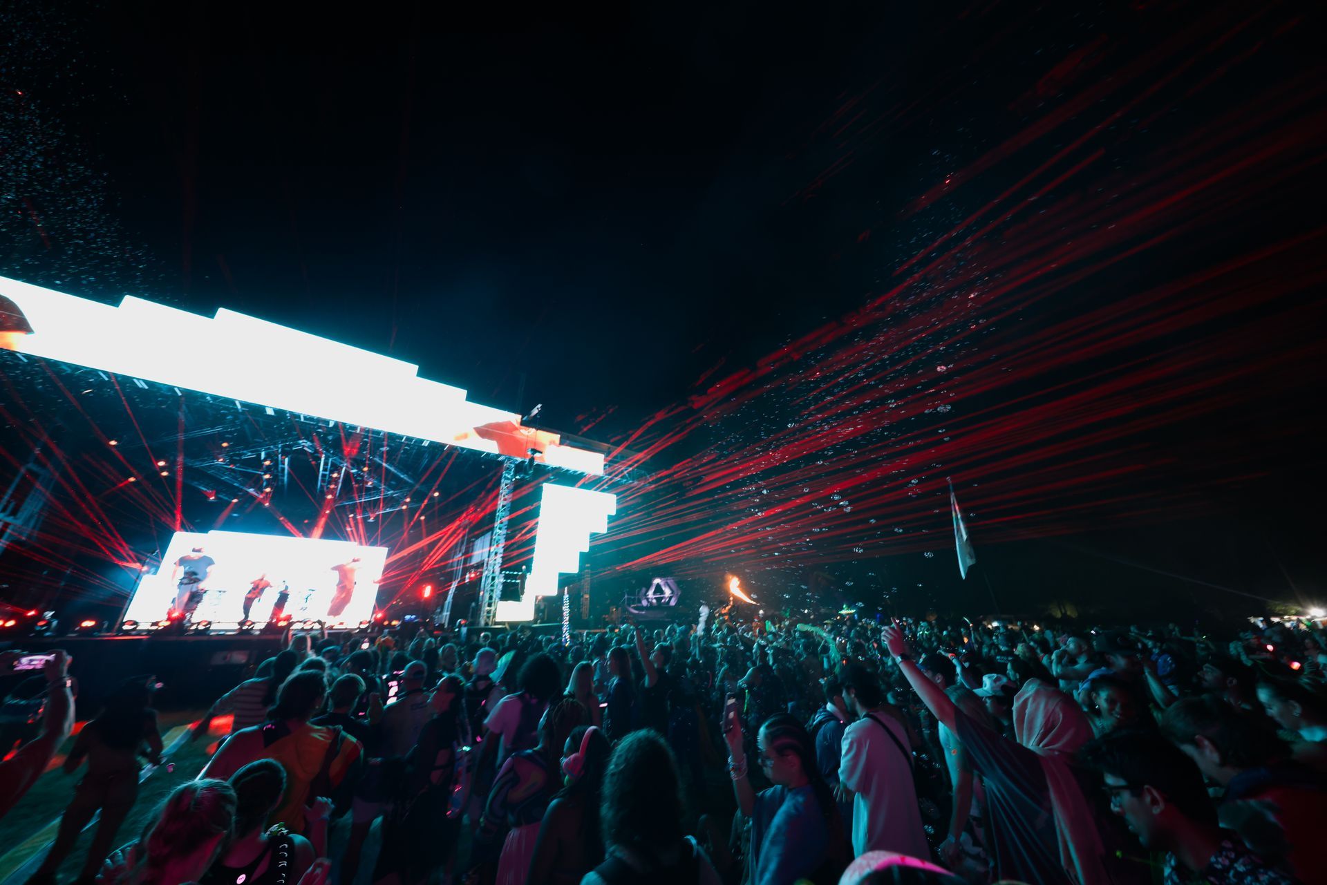 A crowd of people are standing in front of a stage at a concert.