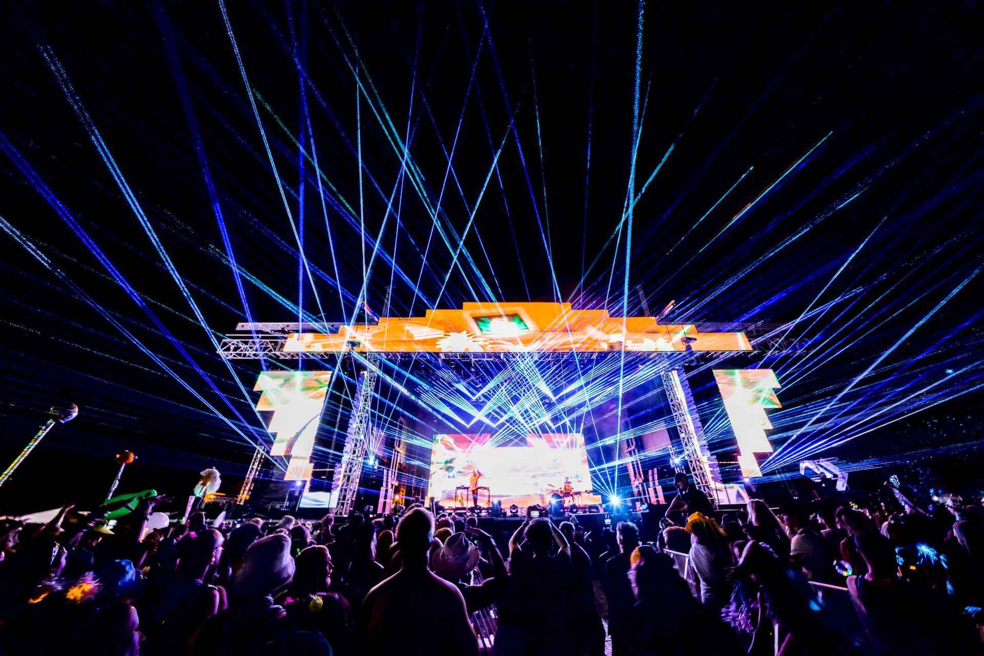 A crowd of people are standing in front of a stage at a concert.