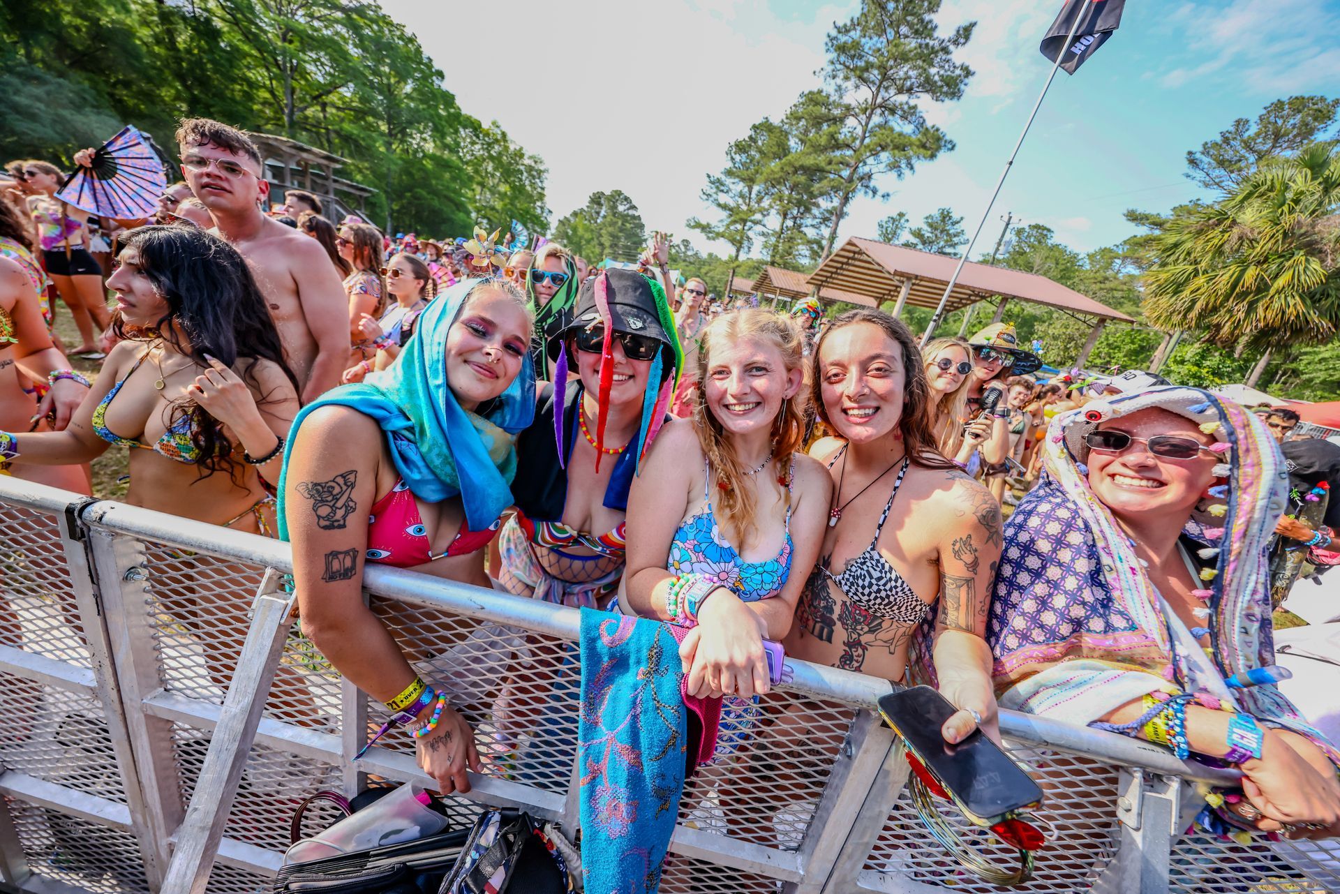 A group of people are standing behind a fence at a music festival.