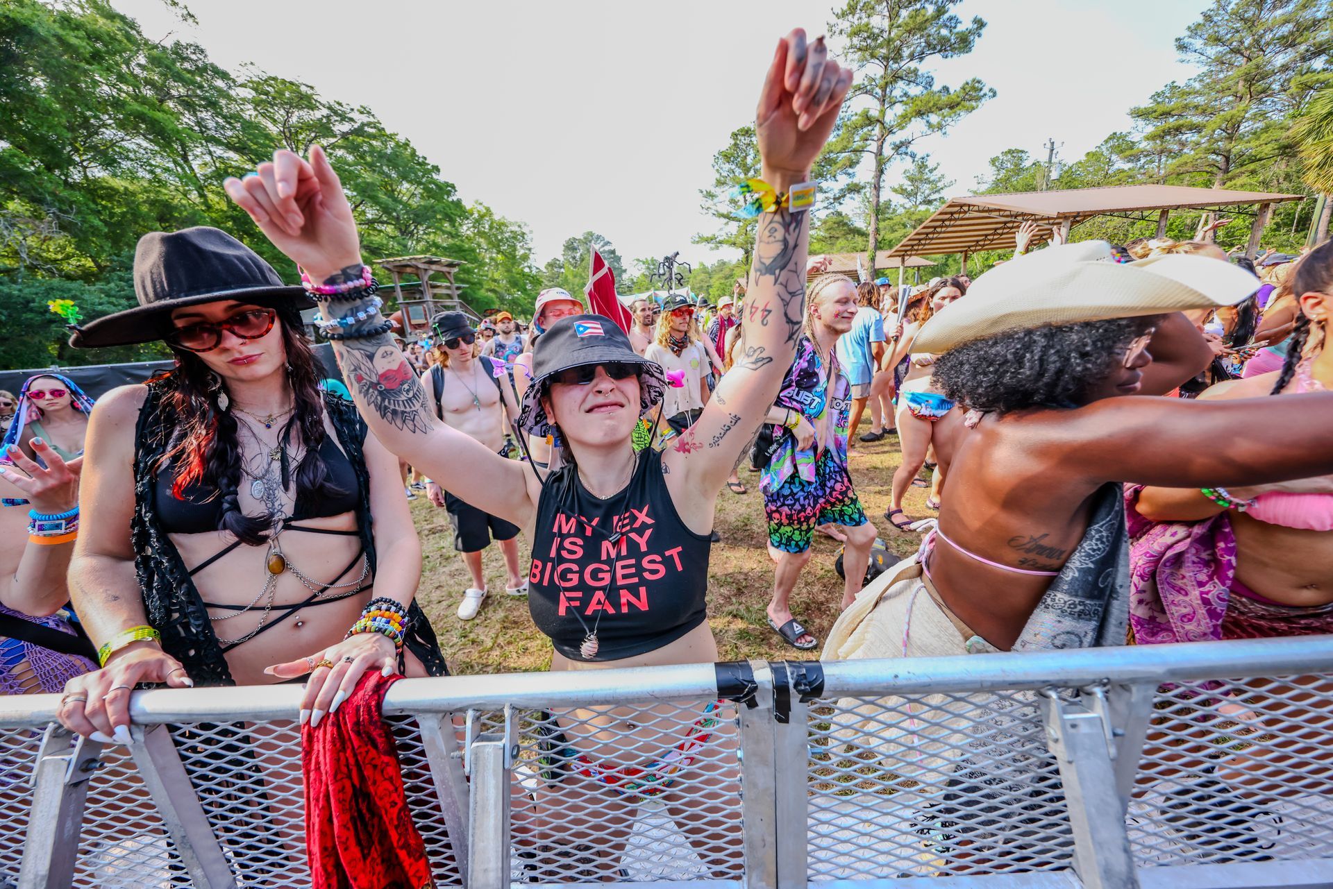 A group of people are standing behind a fence at a music festival.