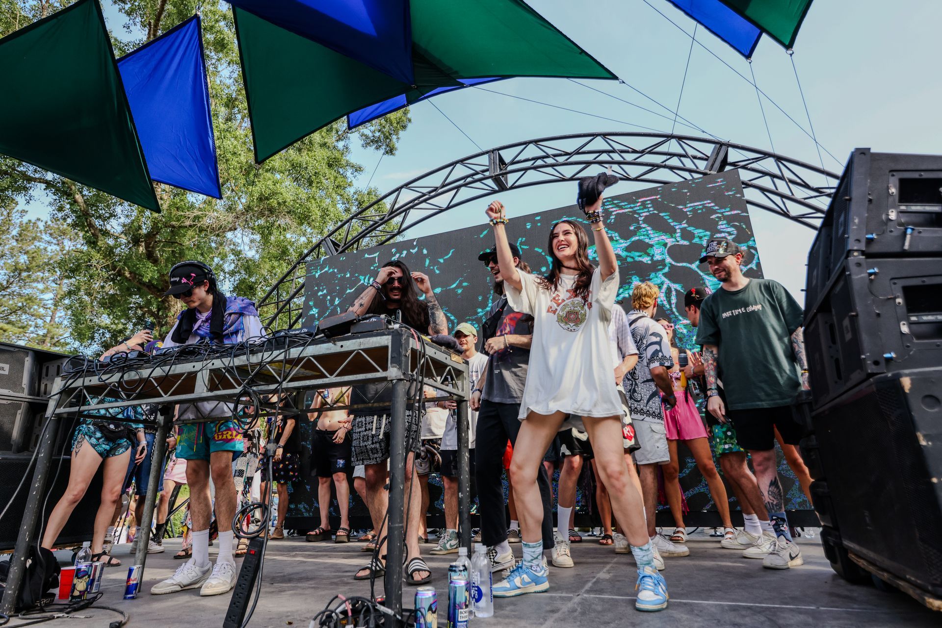 A group of people are dancing on a stage at a music festival.