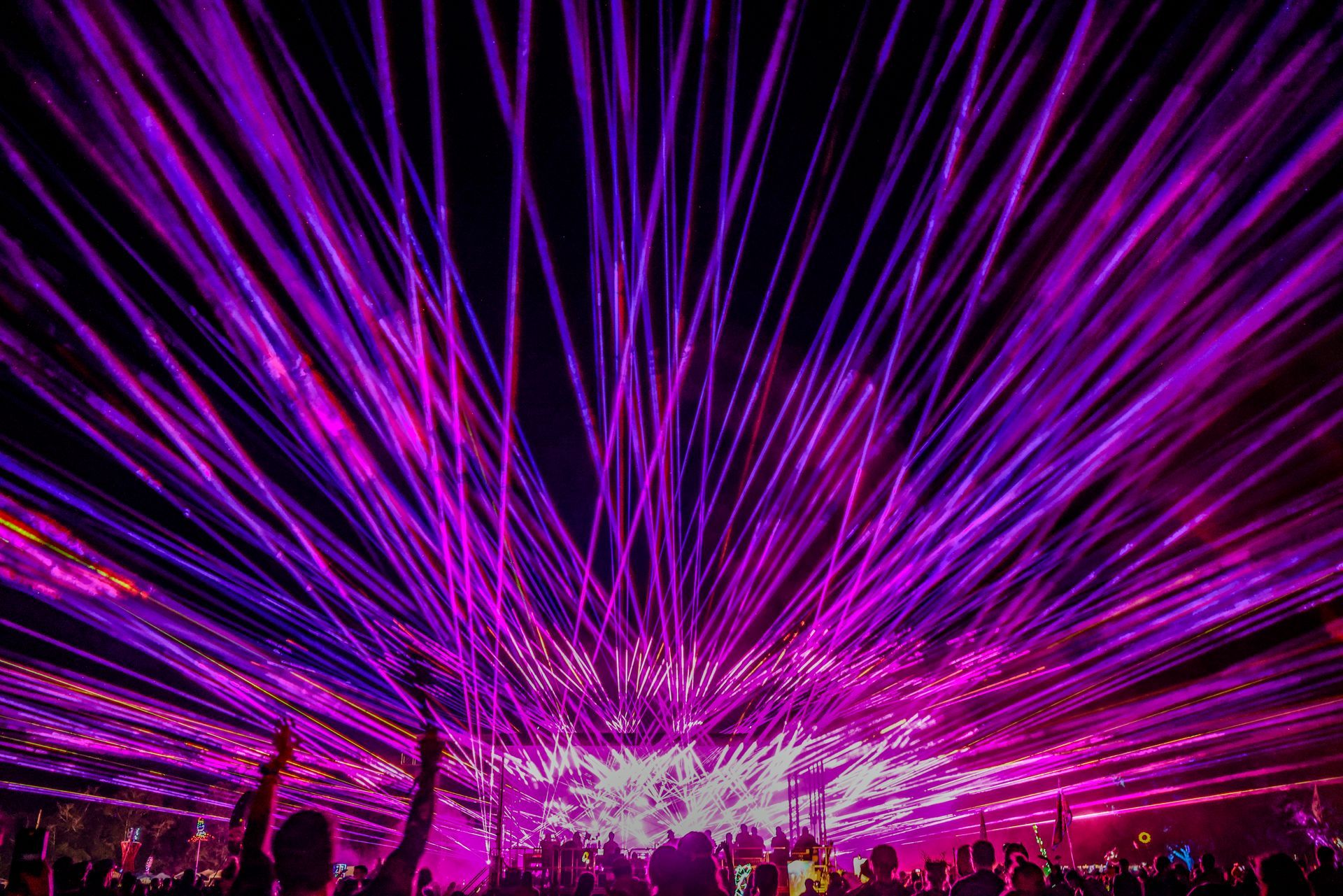 A crowd of people are watching a laser show at a concert.