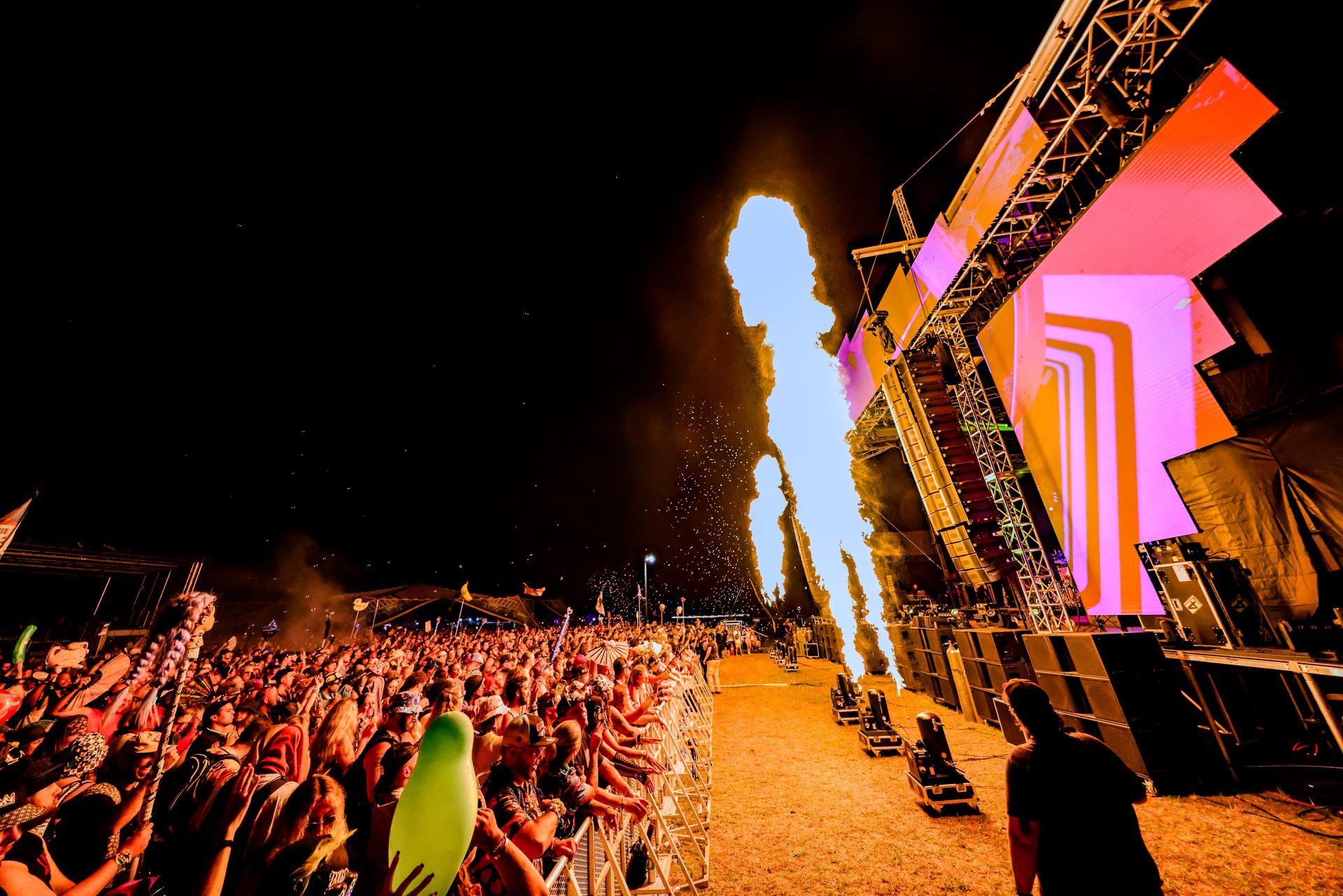 A crowd of people standing in front of a stage at a concert