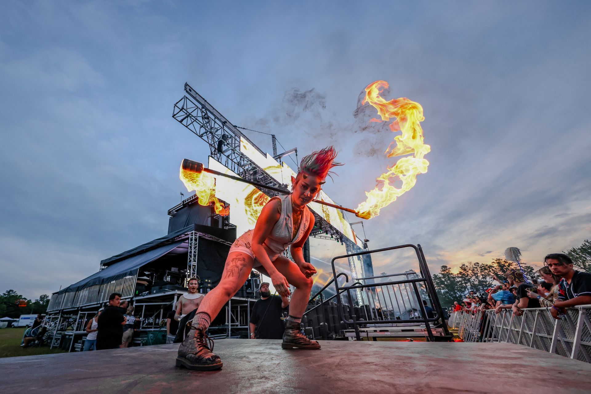 A woman is juggling fire on a stage in front of a crowd.