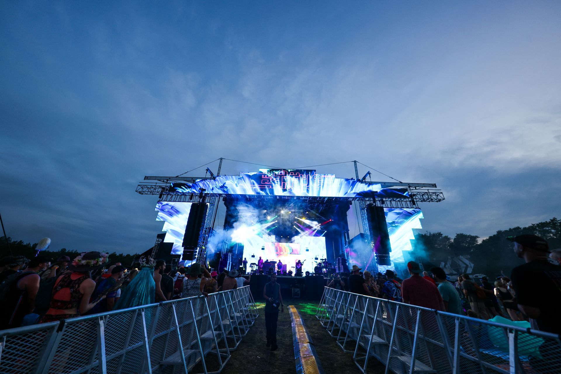 A crowd of people are standing in front of a stage at a concert.