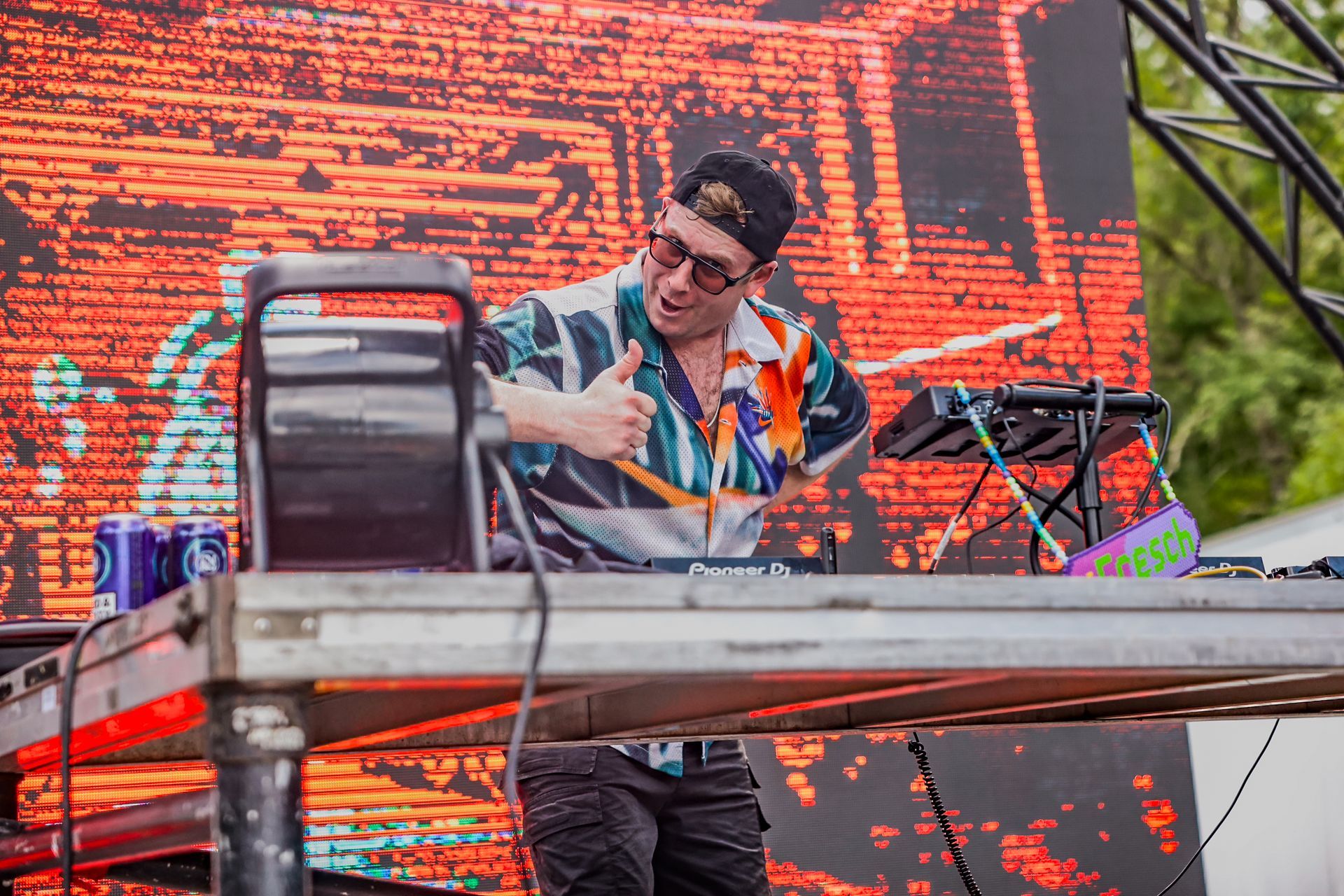 A man is playing a dj set on a stage in front of a large screen.