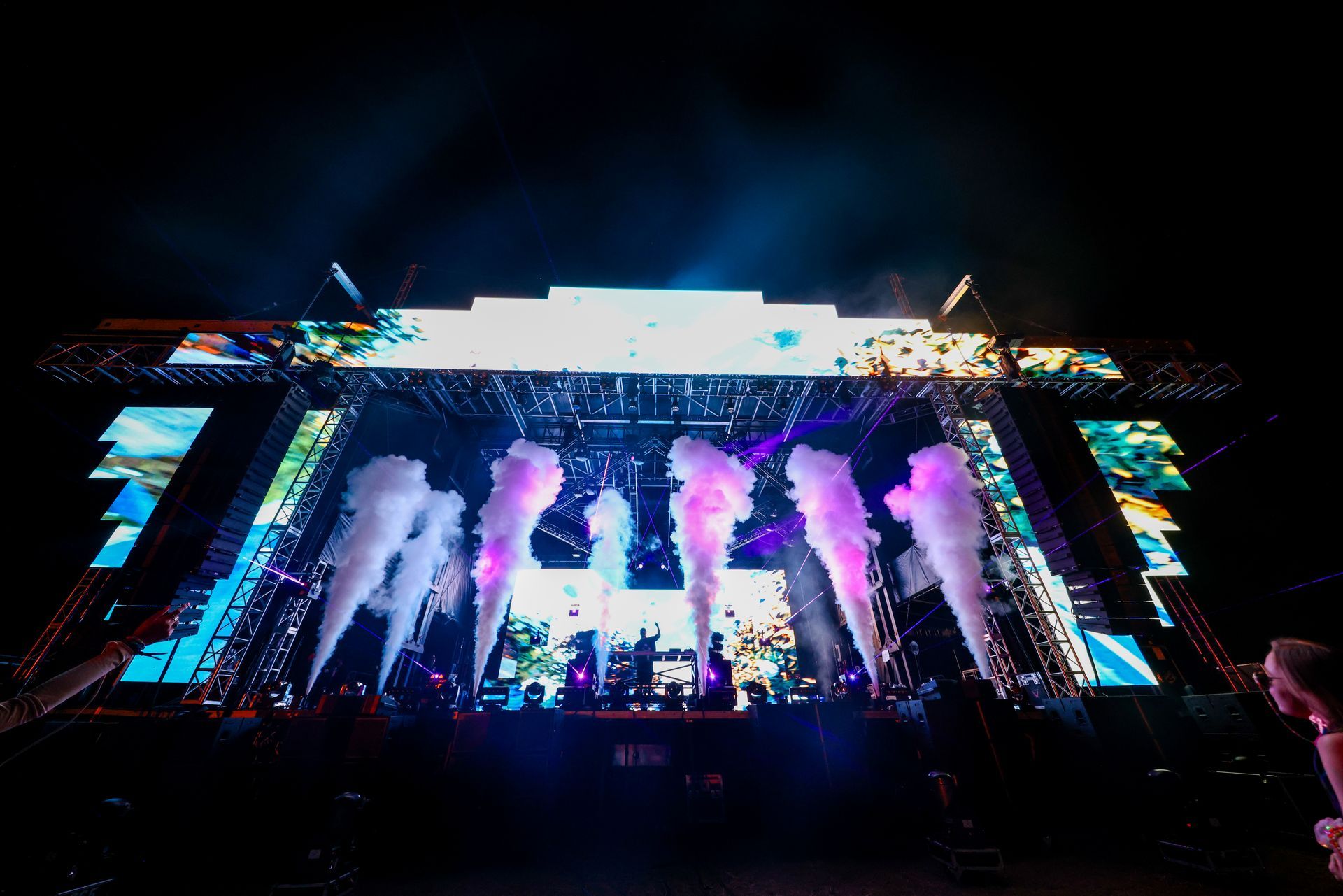 A large stage with smoke coming out of it at a concert.