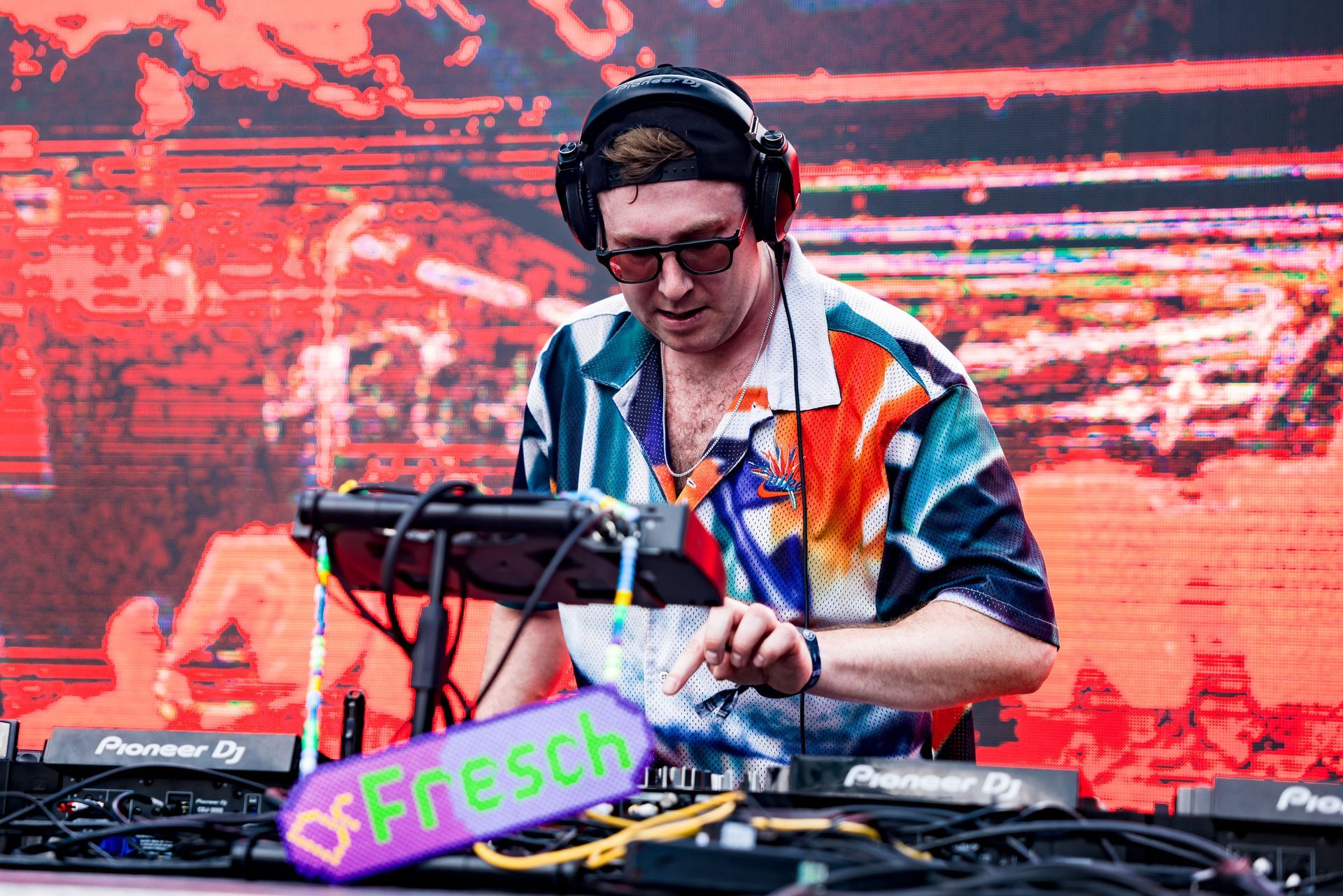 A man wearing headphones is playing a keyboard on a stage.
