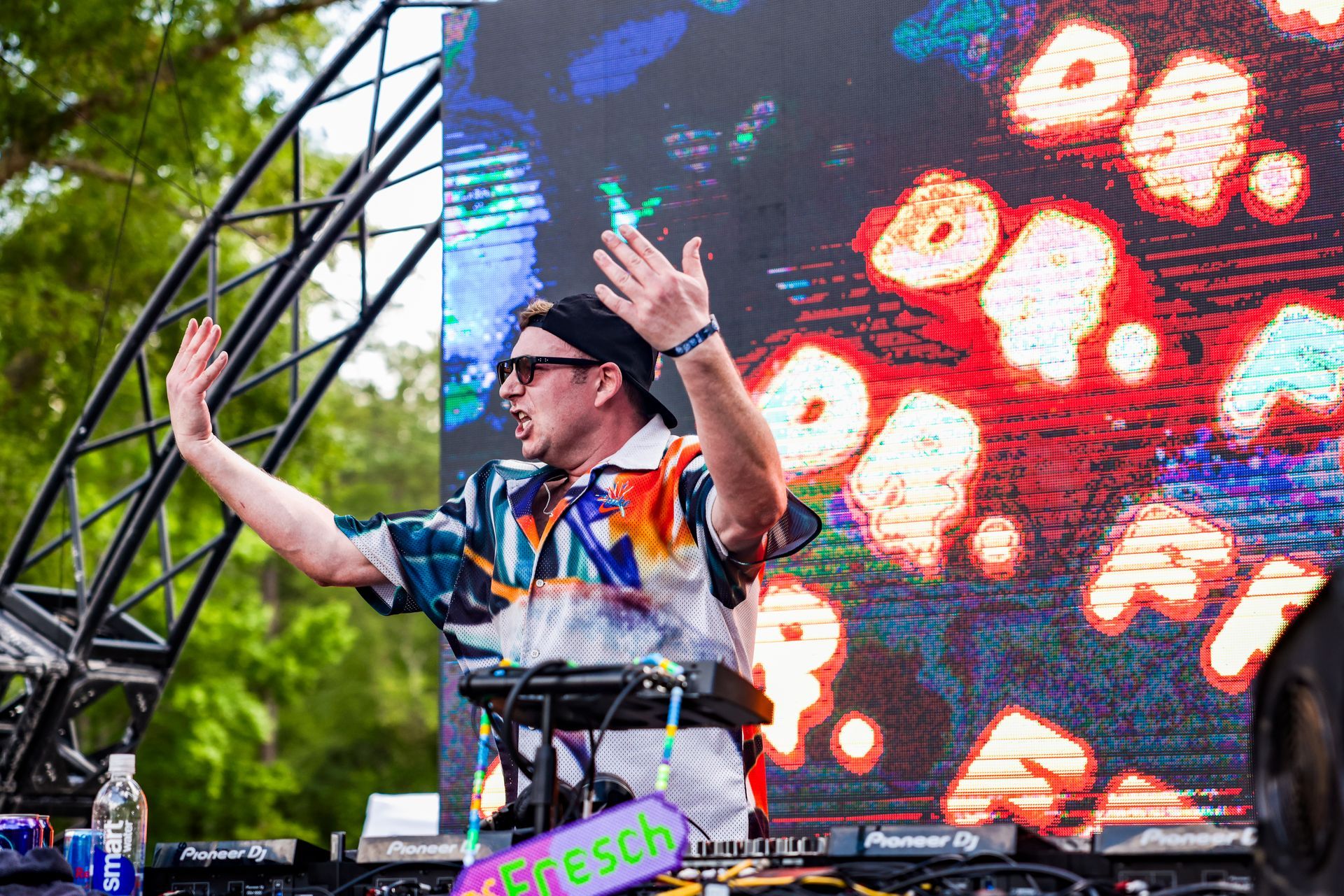 A dj is playing music on a stage in front of a large screen.