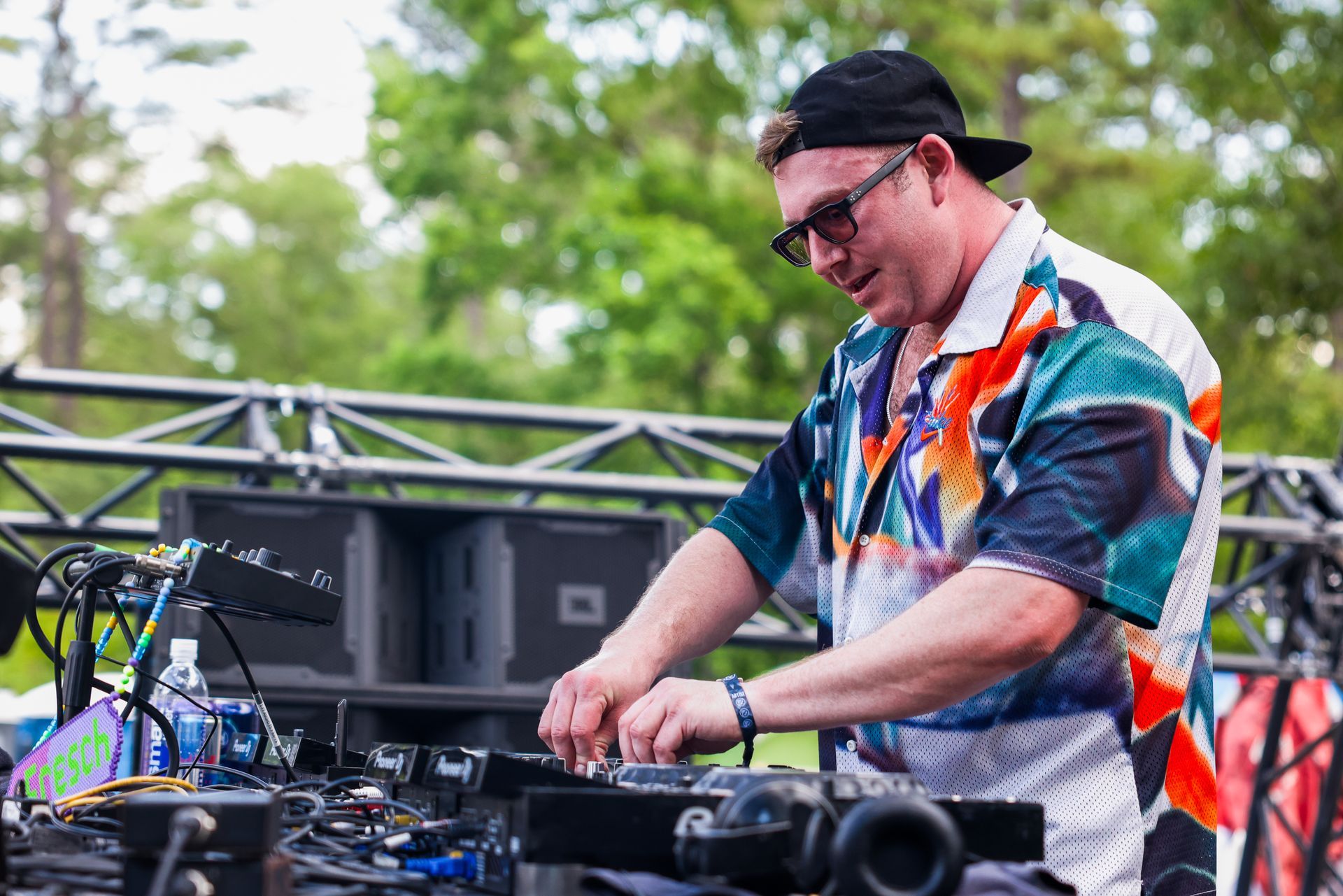A man in a colorful shirt is playing a dj set on a stage.