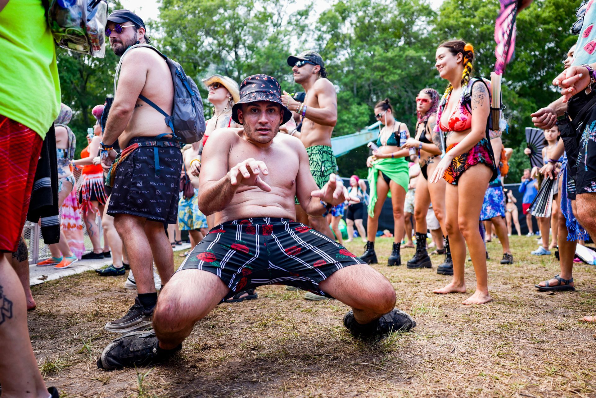 A shirtless man is kneeling down in front of a crowd of people at a festival.