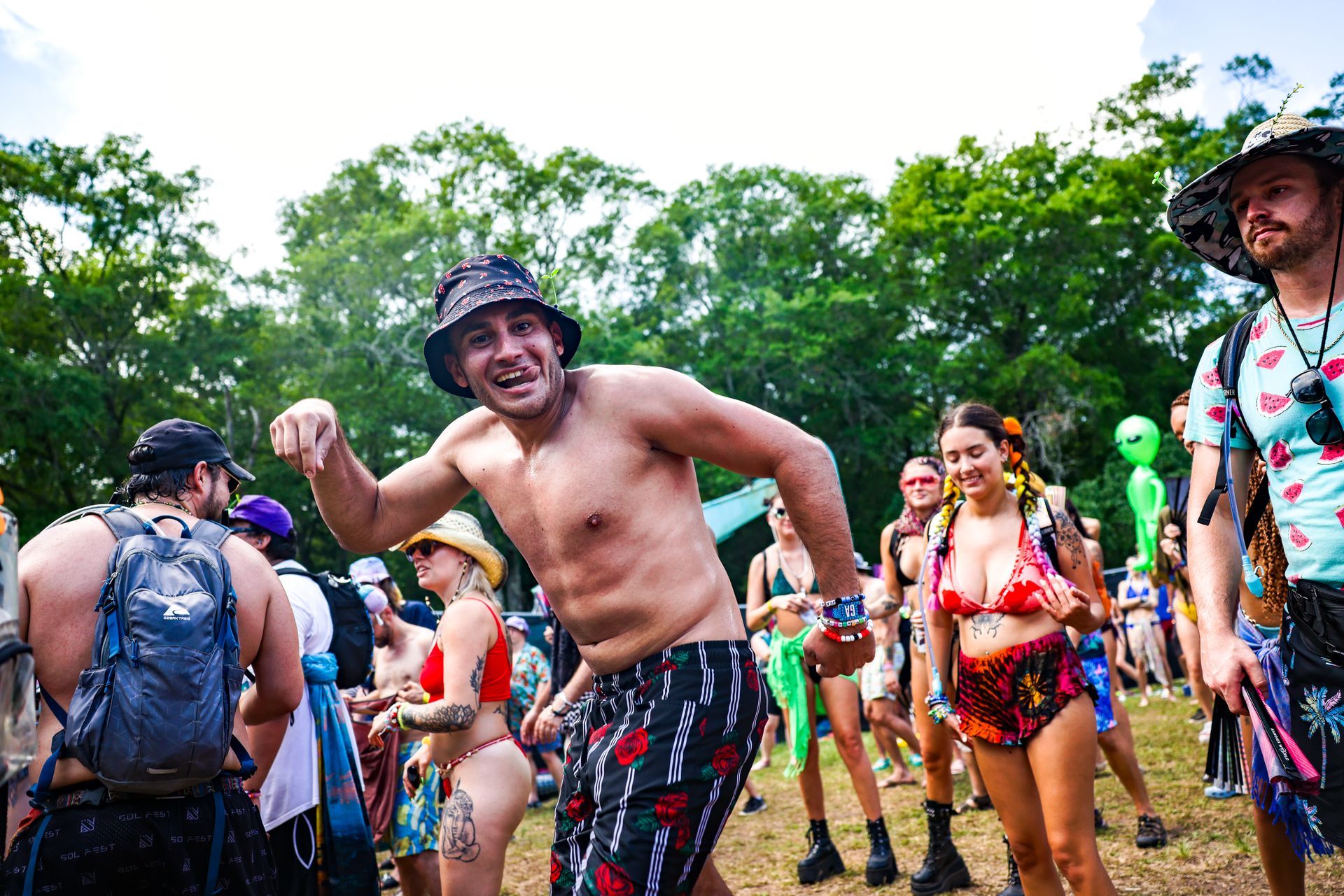 A shirtless man is dancing in a crowd of people at a festival.