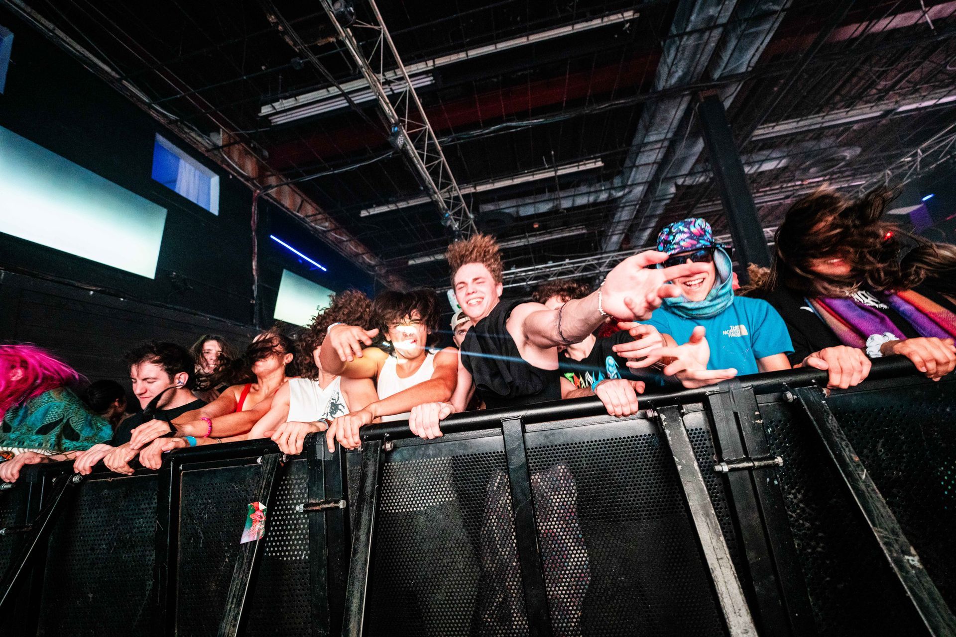 A group of people are standing behind a fence at a concert.