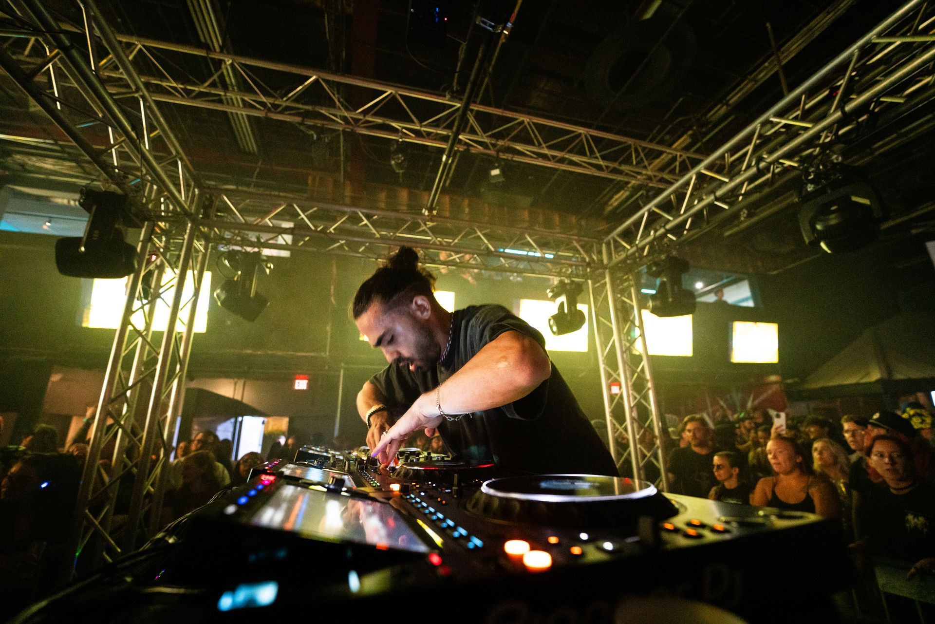 A dj is playing music in front of a crowd in a club.