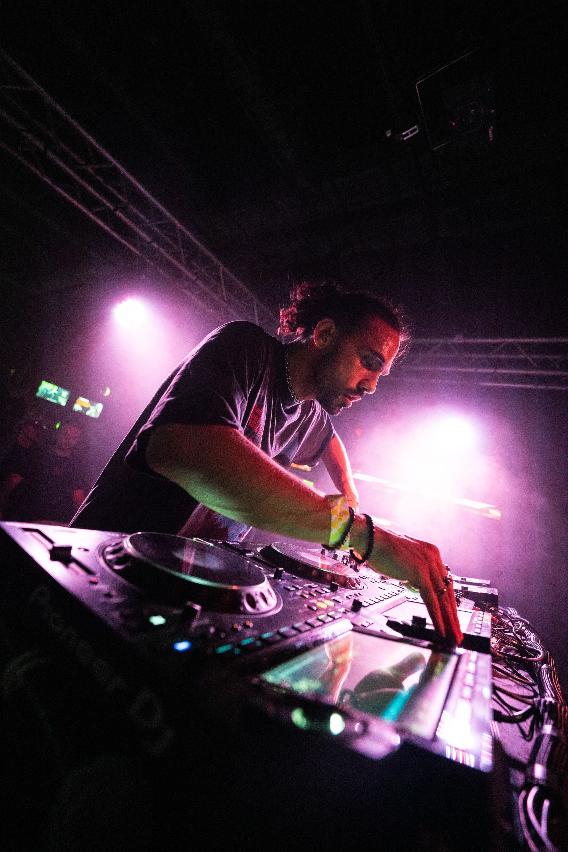 A man is playing a dj set in a dark room.