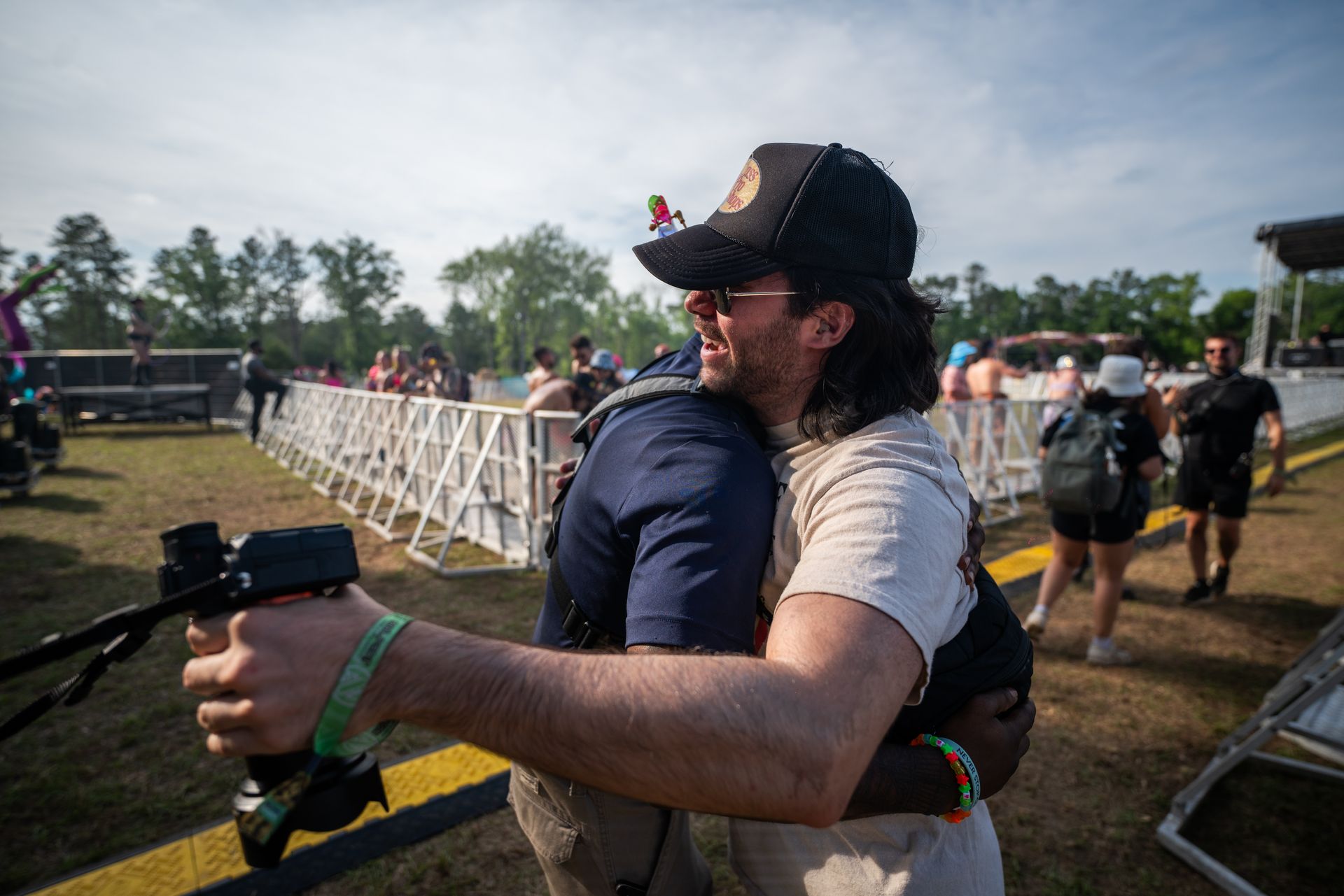 A man is hugging another man while holding a camera.