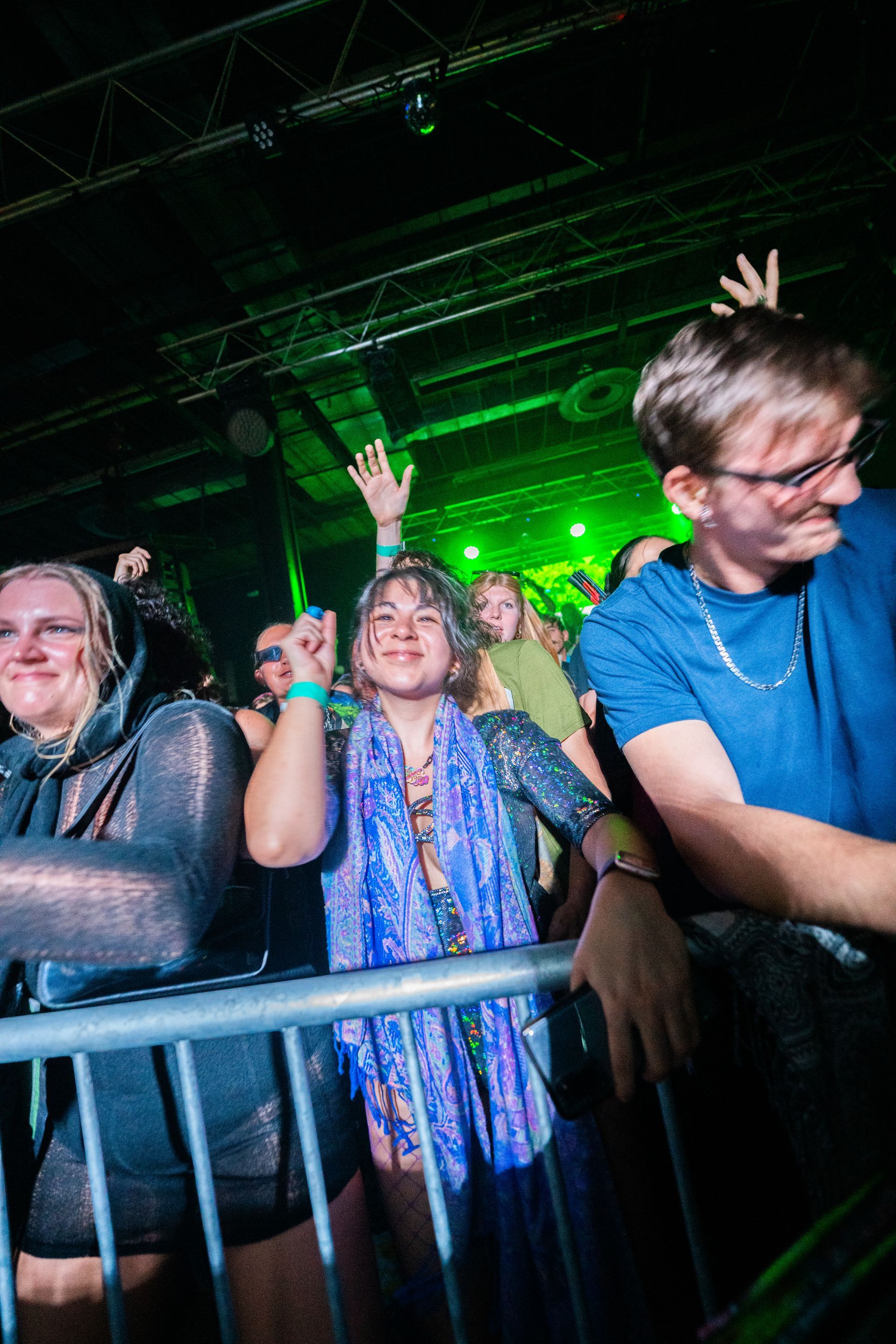 A group of people are standing behind a fence at a concert.