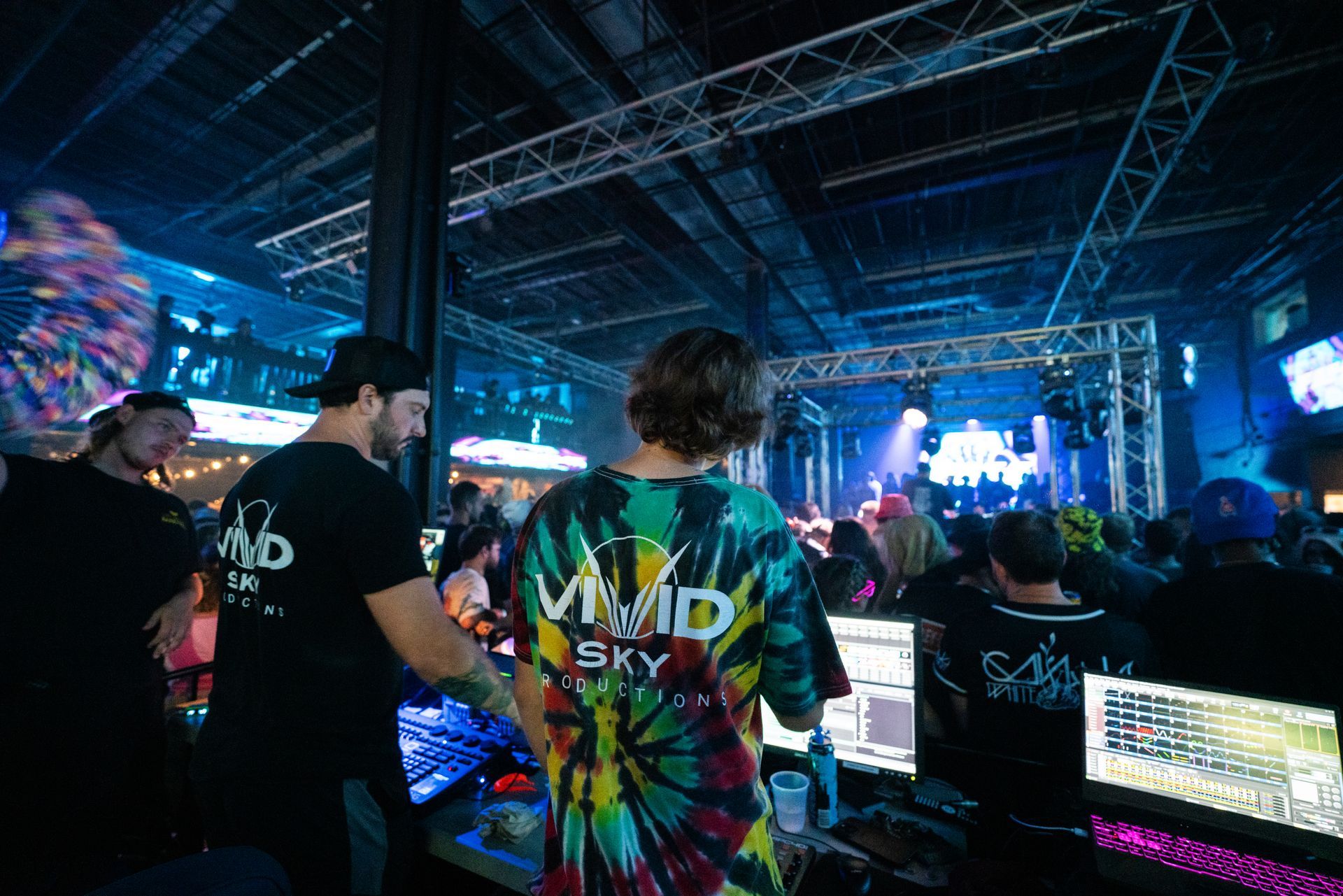 A man in a tie dye shirt is standing in front of a crowd at a concert.