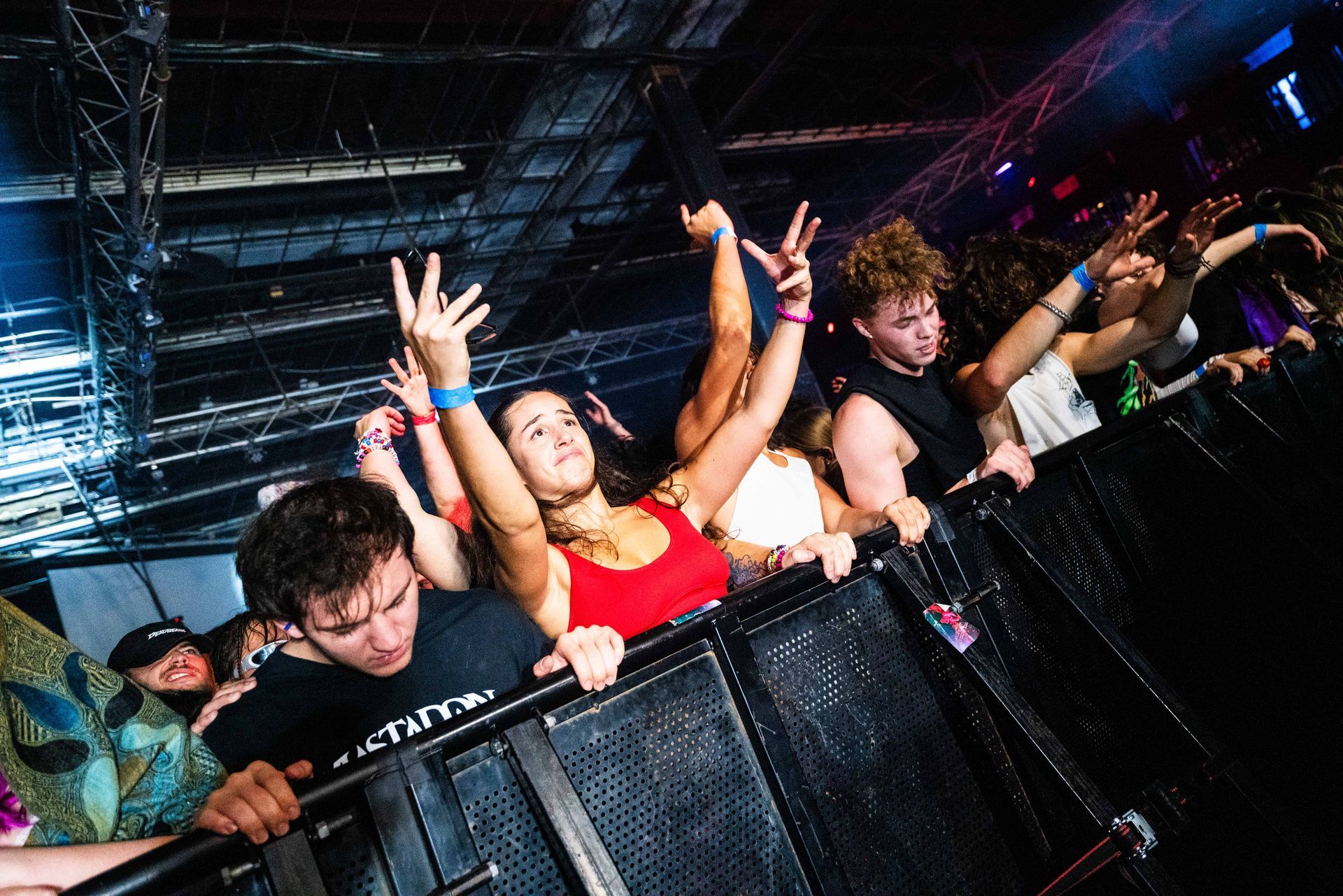 A crowd of people are standing behind a fence at a concert.