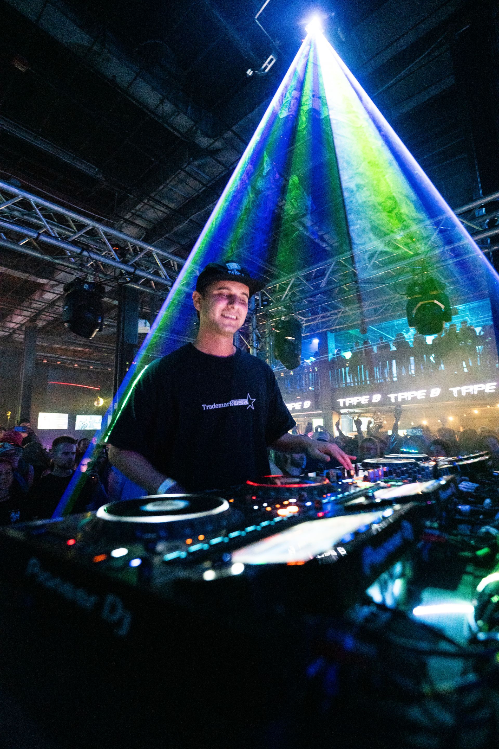 A man is standing in front of a dj mixer in a dark room.