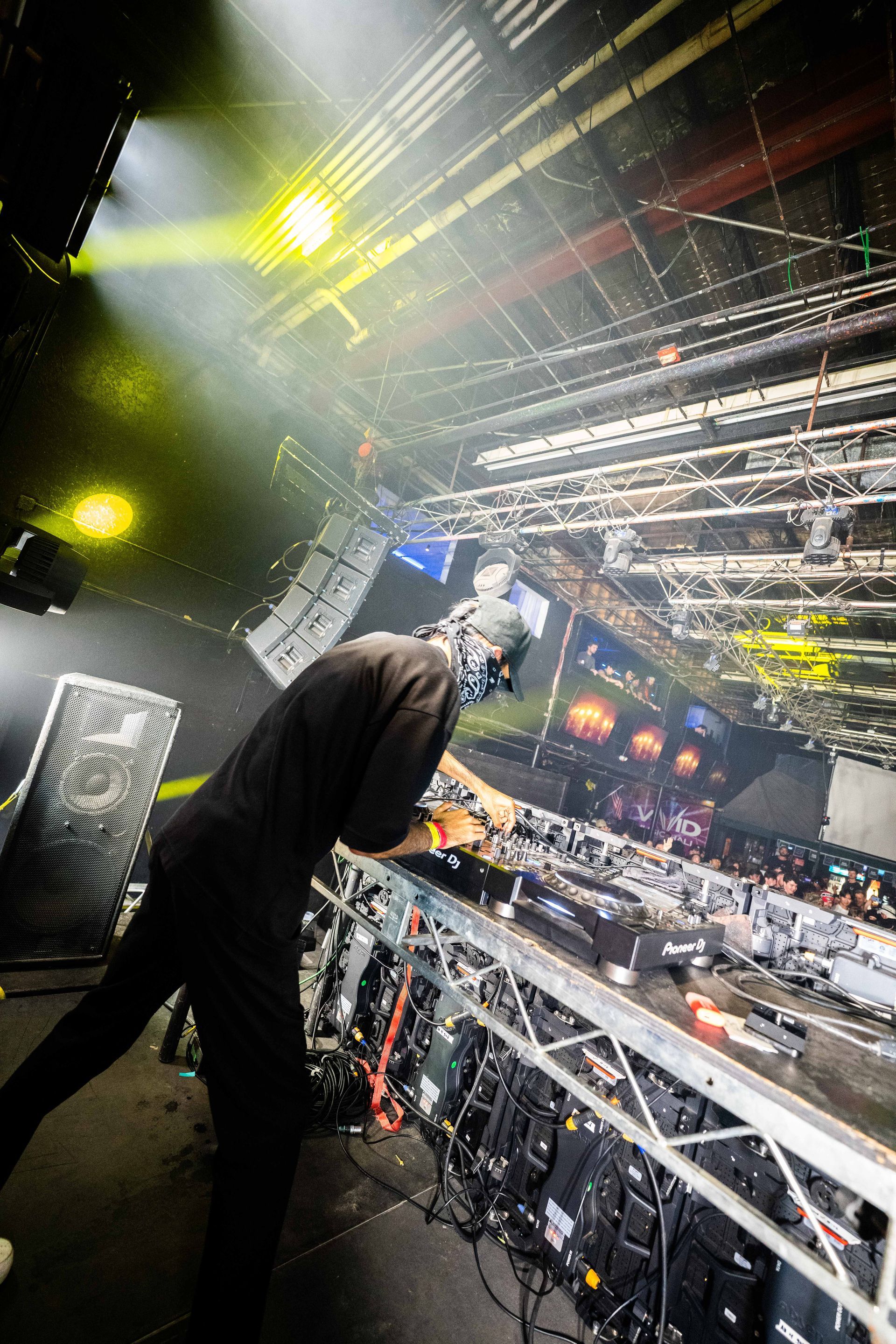 A man is playing a dj set on a stage in a dark room.