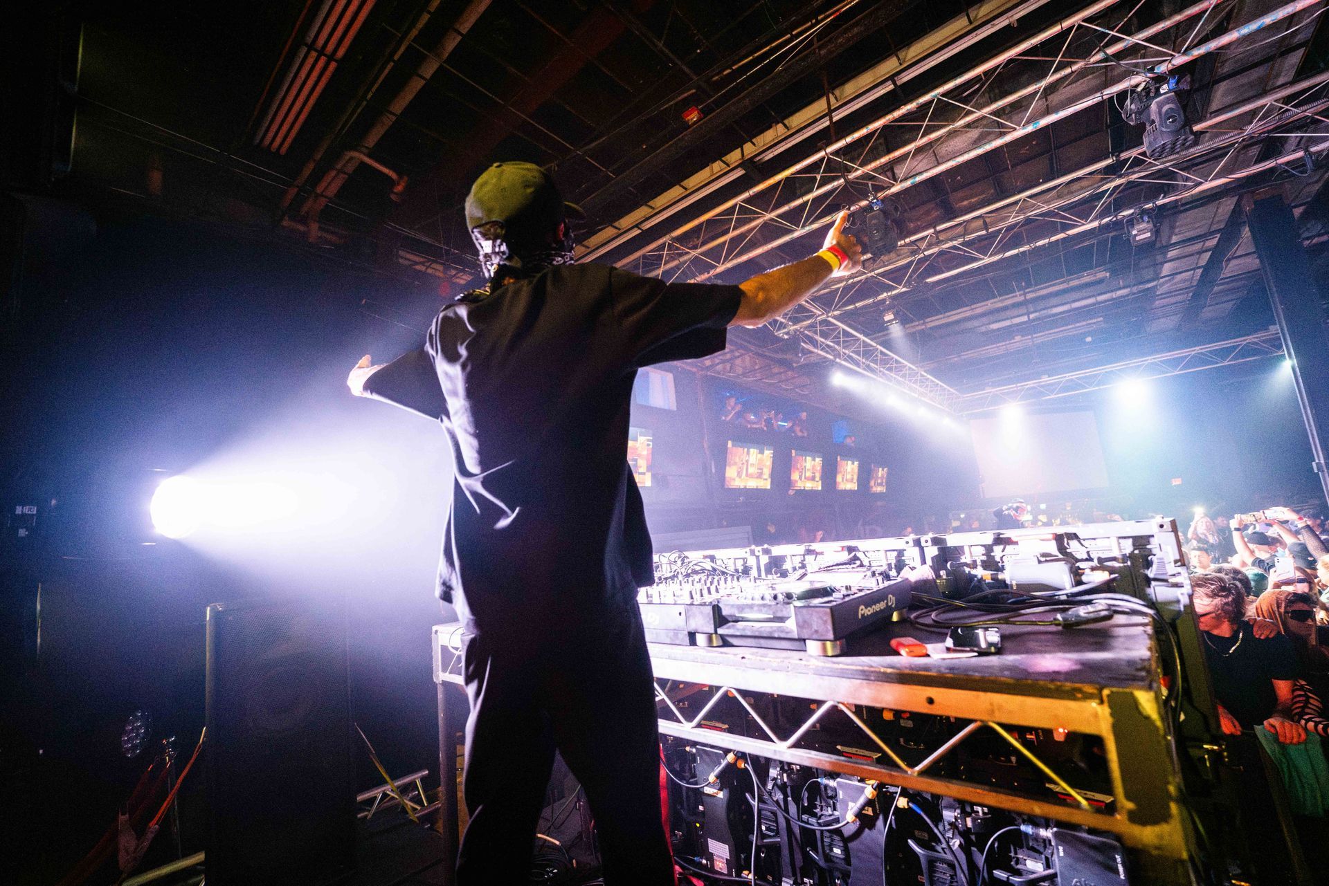 A man is standing on a stage with his arms outstretched in front of a crowd.