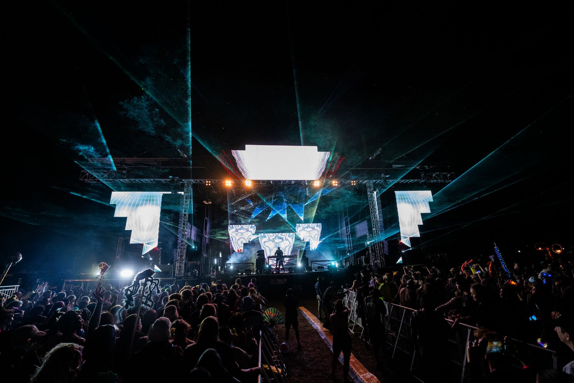 A crowd of people are standing in front of a stage at a concert.