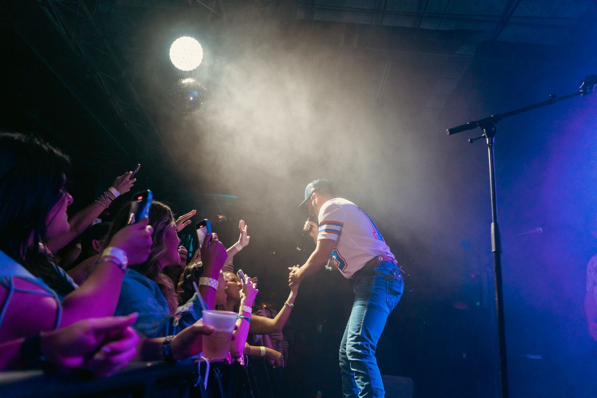 A man is singing into a microphone on a stage in front of a crowd.
