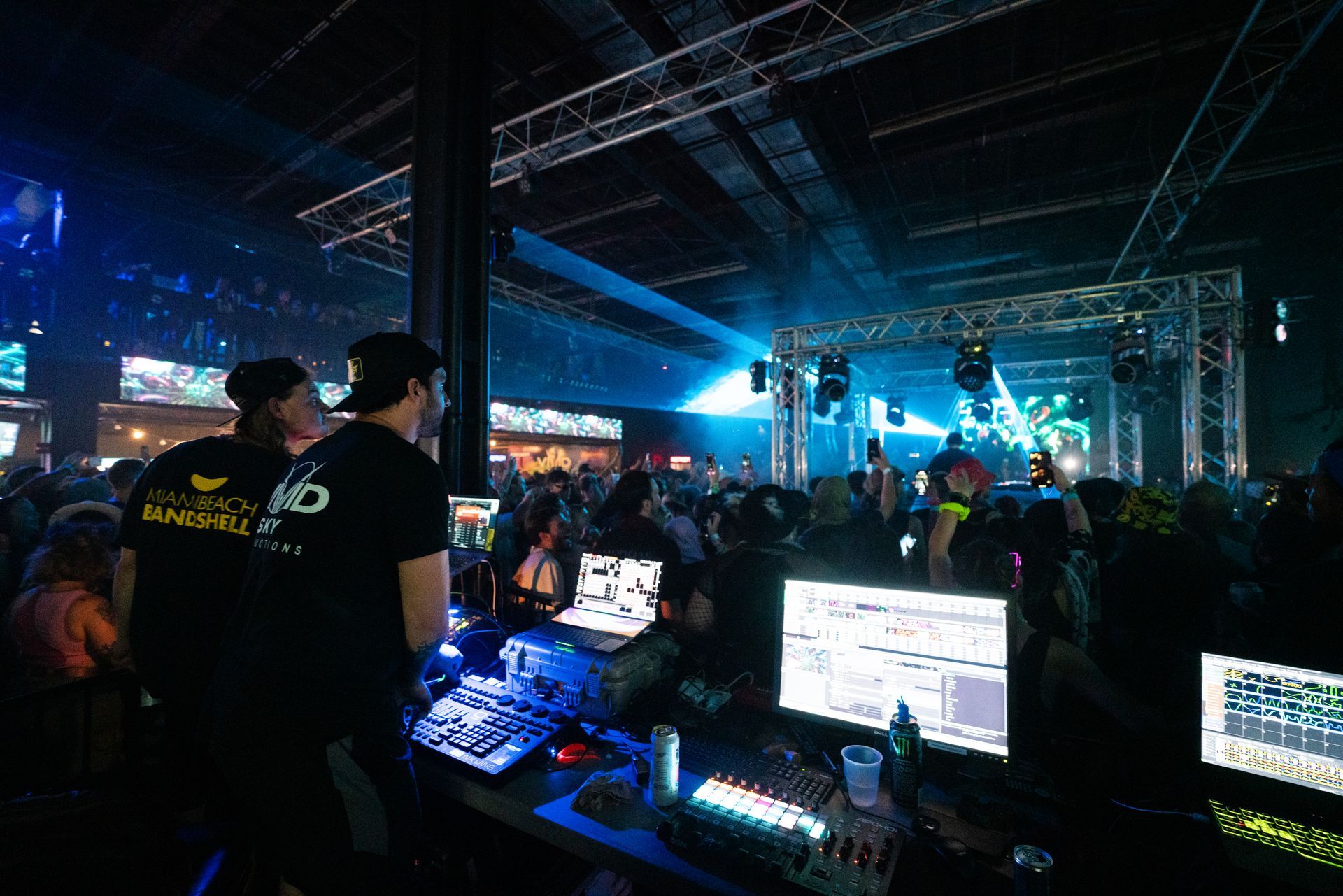 A group of people are standing in a dark room with a lot of monitors.