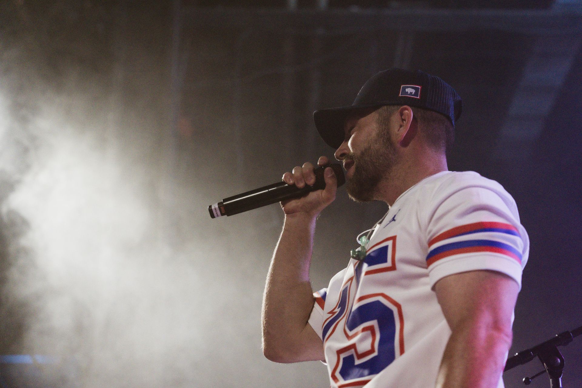 A man in a football jersey is singing into a microphone.