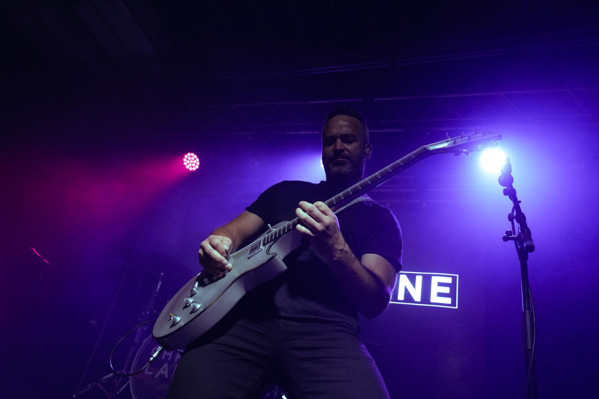 A man is playing a guitar on a stage in front of a microphone.