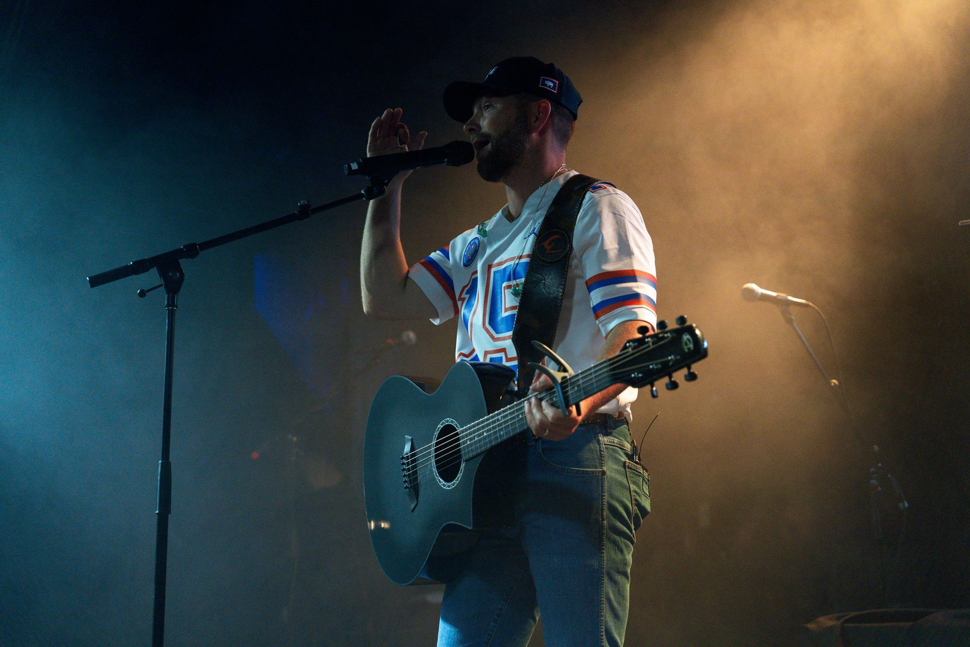 A man is playing a guitar and singing into a microphone on a stage.